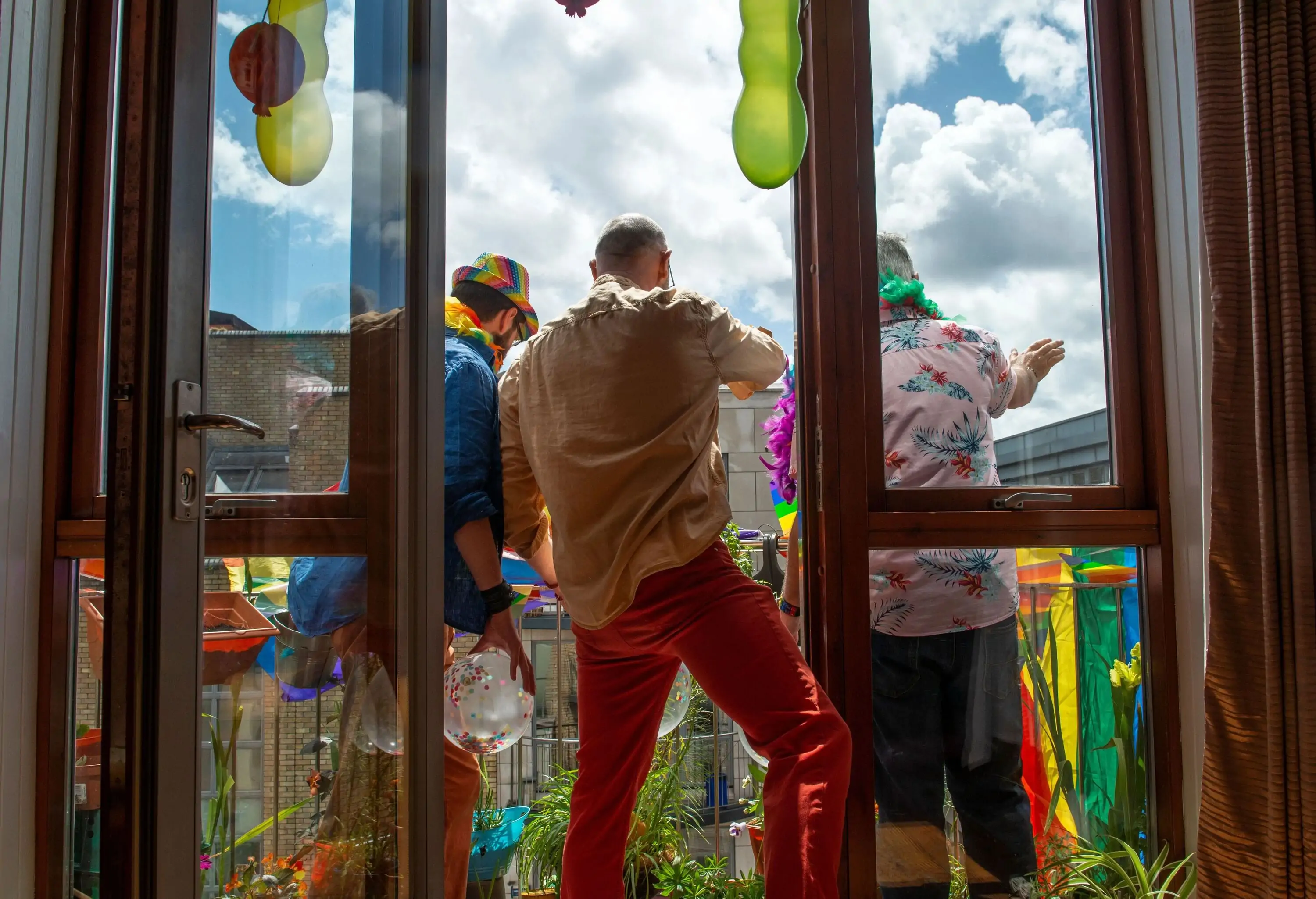 Group of gay men celebrating Gay Pride at home from their balcony