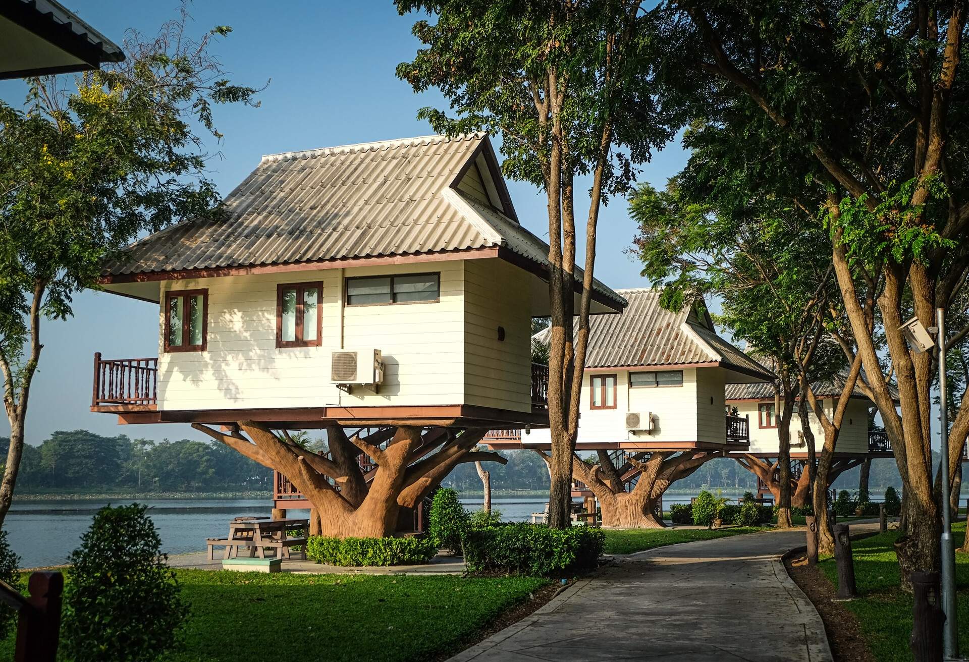 A row of tree houses along the shore lined with concrete pathways and lush trees.