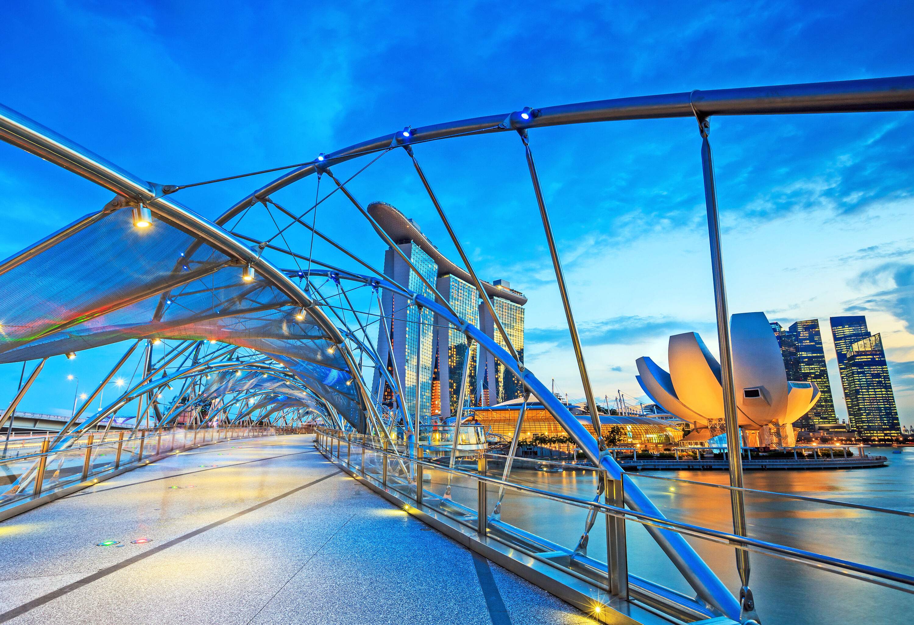 The Helix Bridge, an architectural marvel inspired by the shape of a DNA strand, elegantly spans across the river.