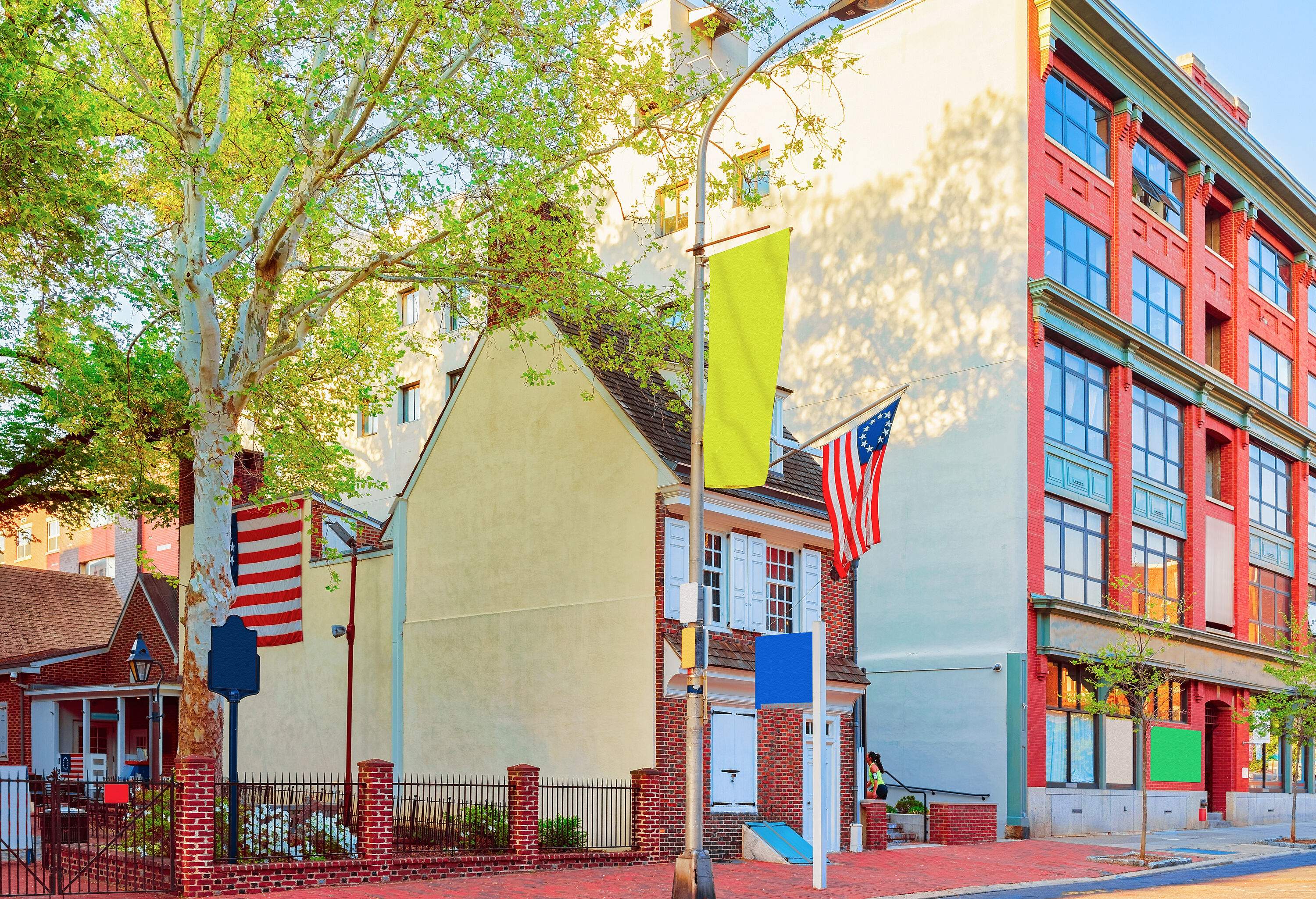 The Betsy Ross House and an adjacent building with glass-paned windows standing out on a vibrant Philadelphia street.