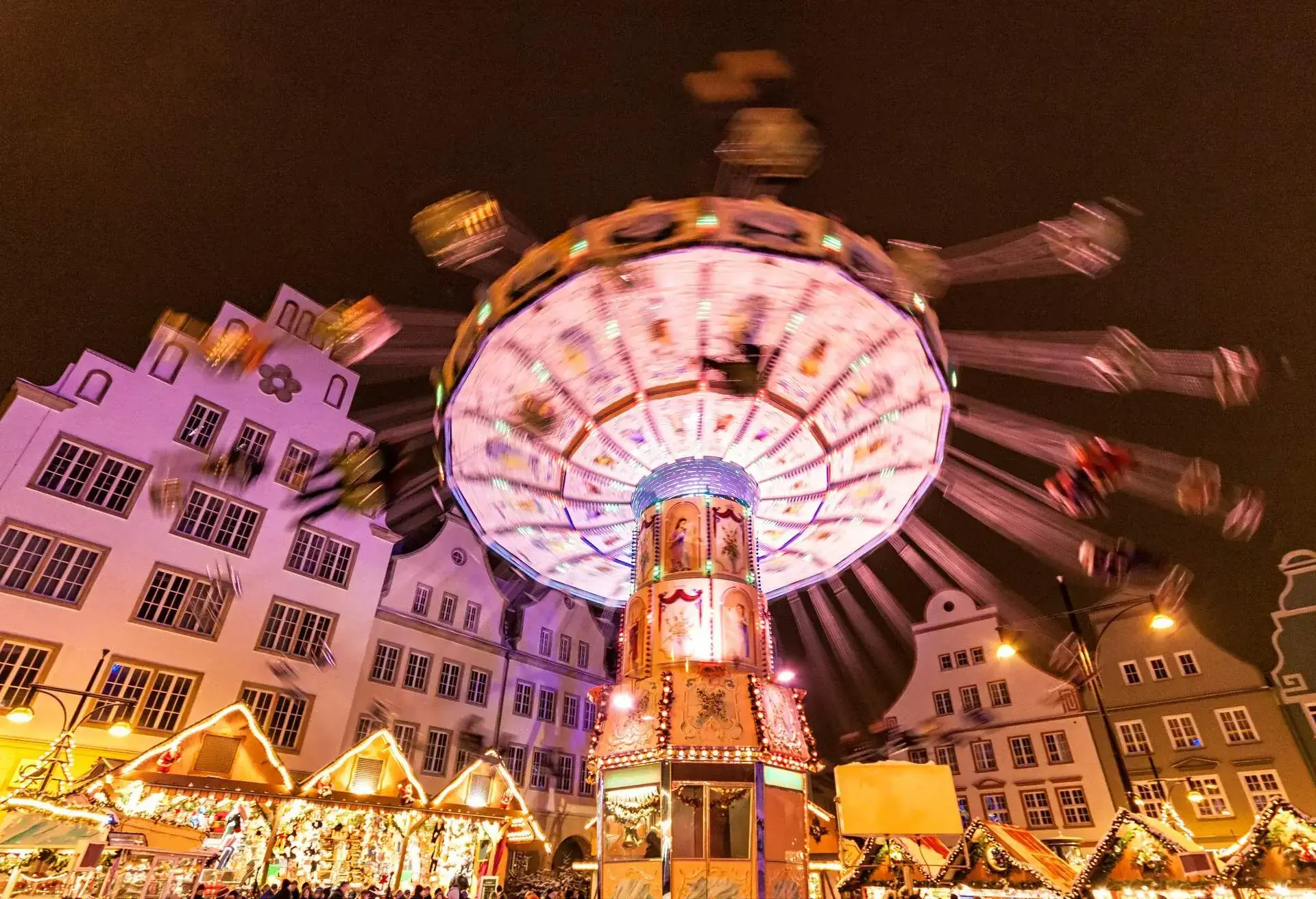 A spinning swing carousel surrounded by bright Christmas booths.