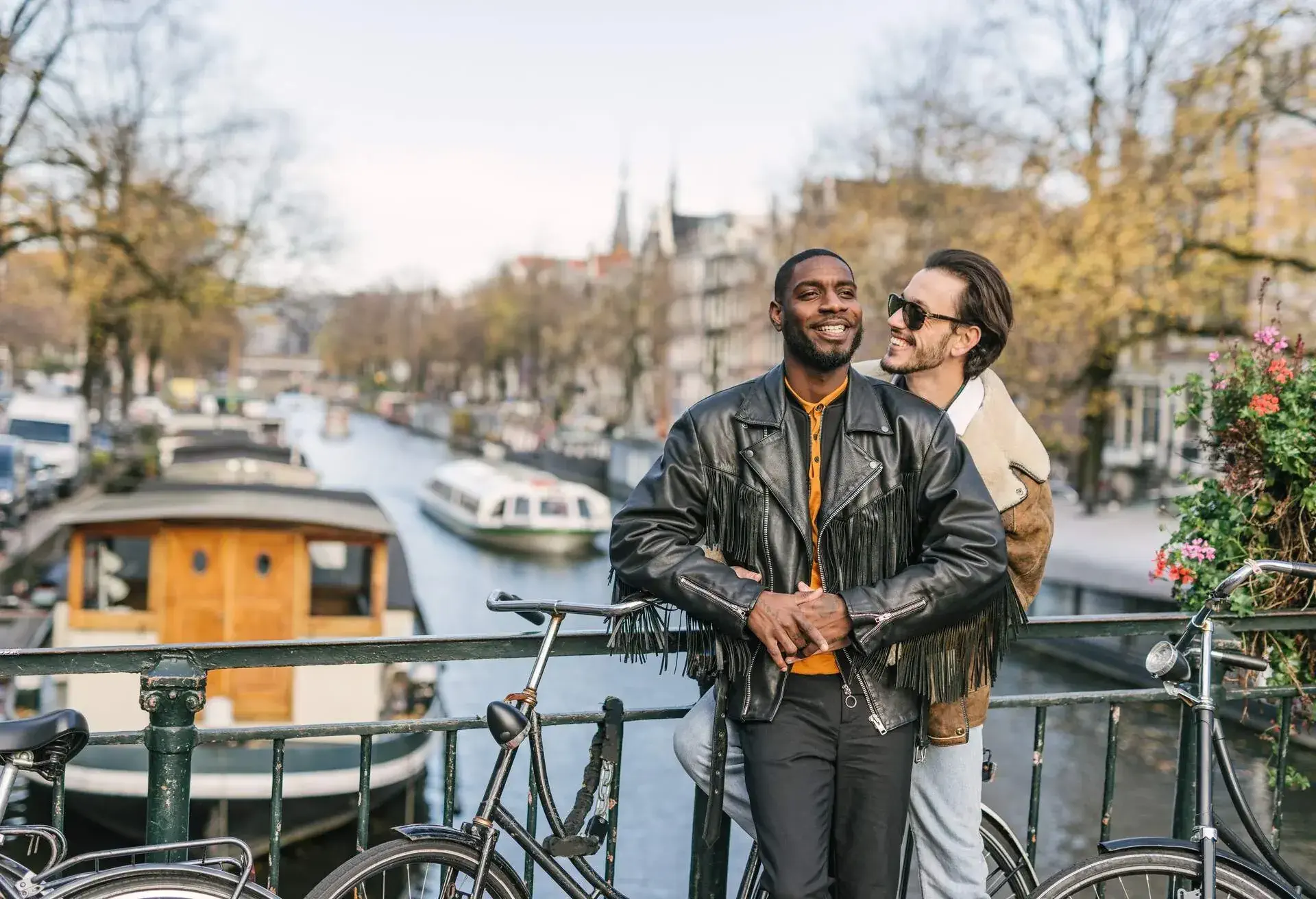 Modern gay couple enjoying the city break in late autumn or early winter in sunny Amsterdam 