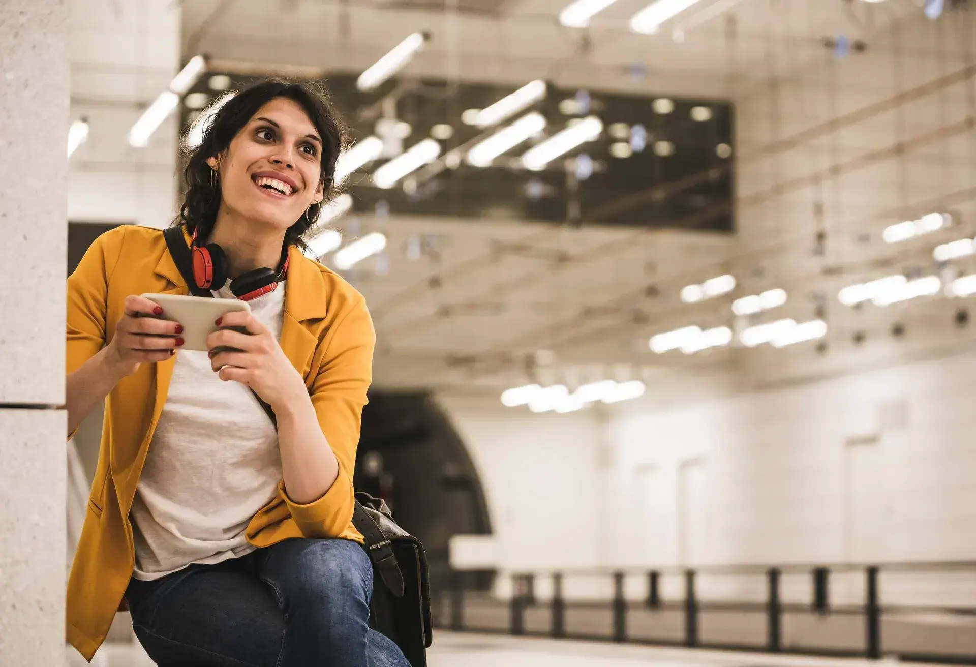 A smiling person in the airport on their smartphone