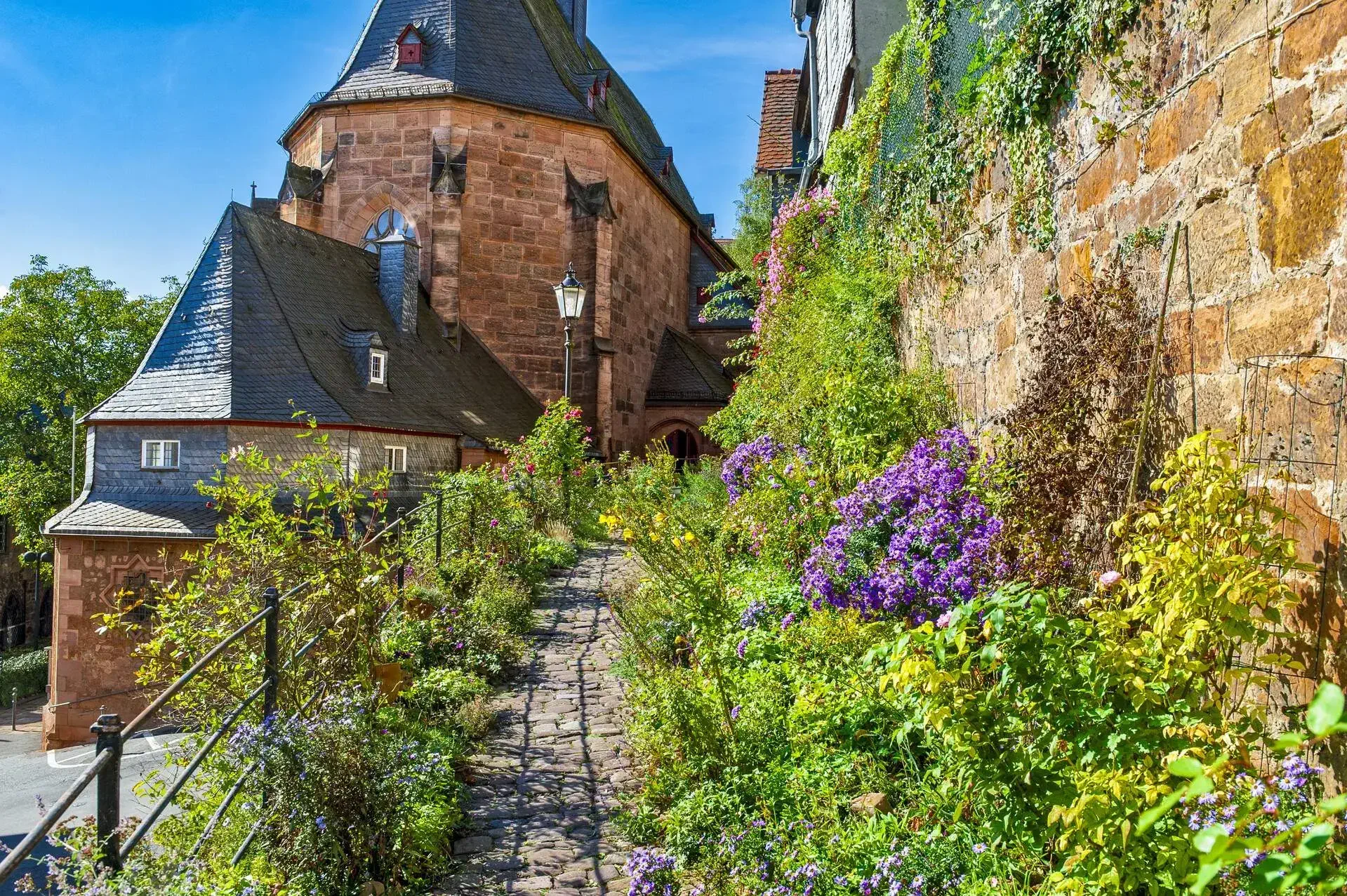 The "Kugelkirche" in the historic old town of Marburg an der Lahn with a footpath framed by flowers
