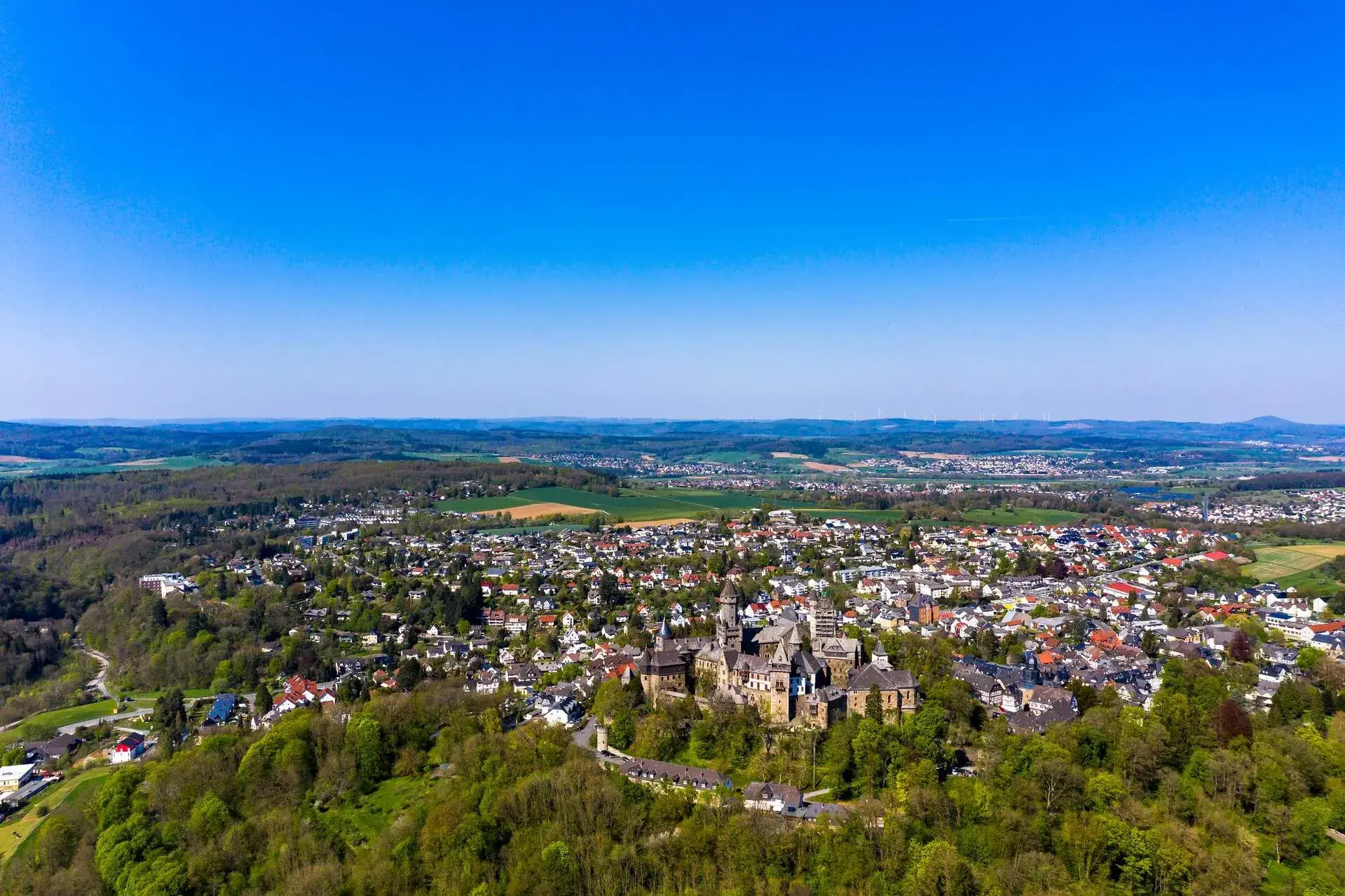 A beautiful cityscape of a town in the middle of the woods that goes all the way to the horizon. 