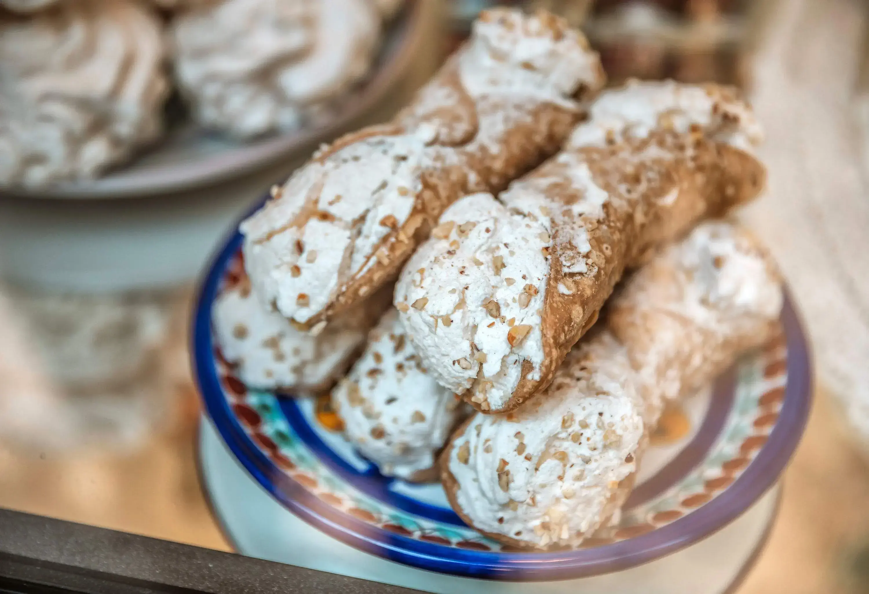 A plate stacked with tube-shaped fried dough with creamy fillings.