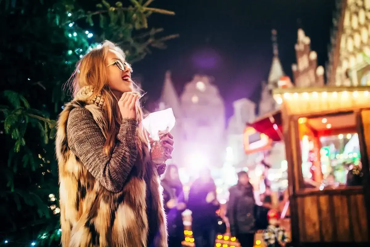 Street portrait of smiling young woman with glasses on the festive Christmas market