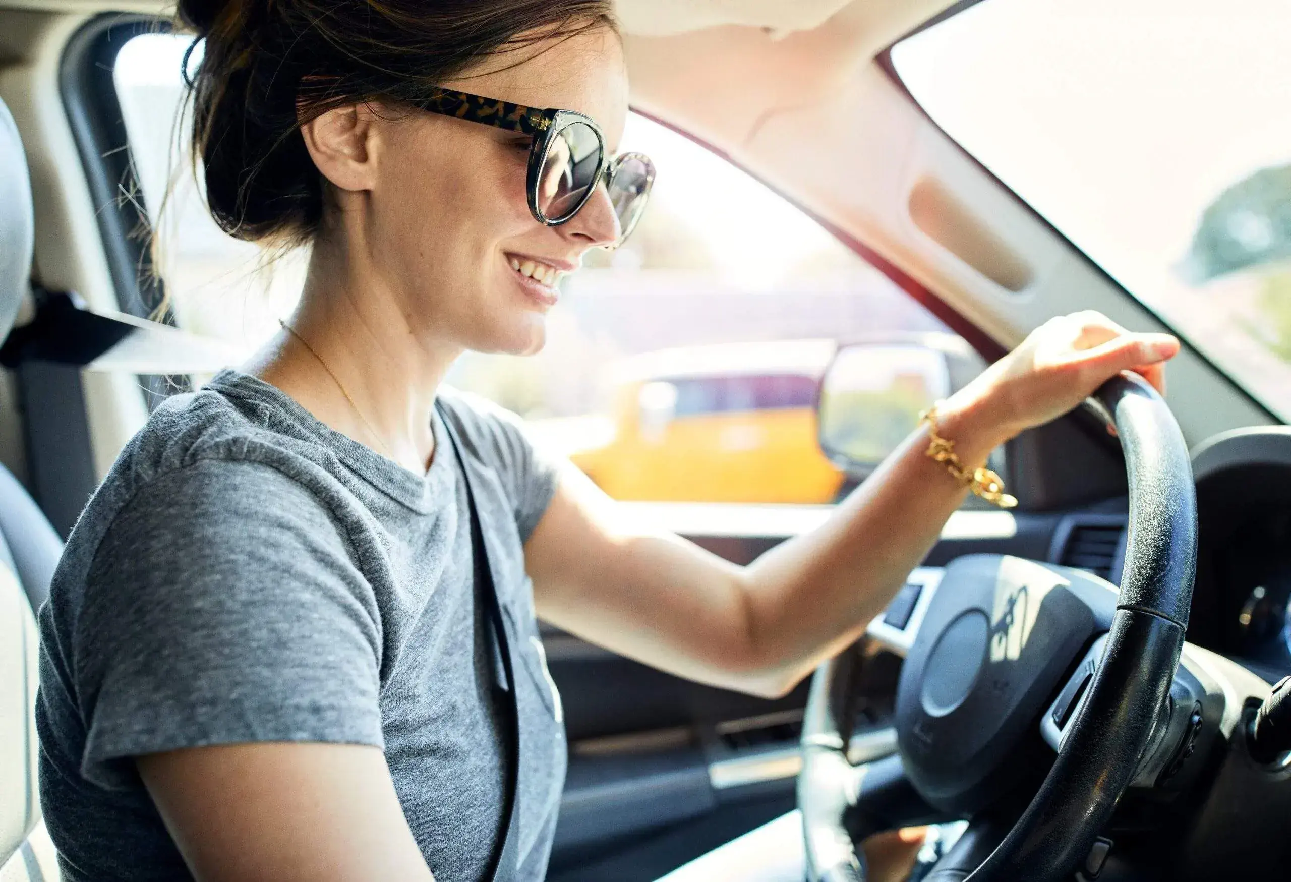 A woman with dark hair and sunglasses inside a car