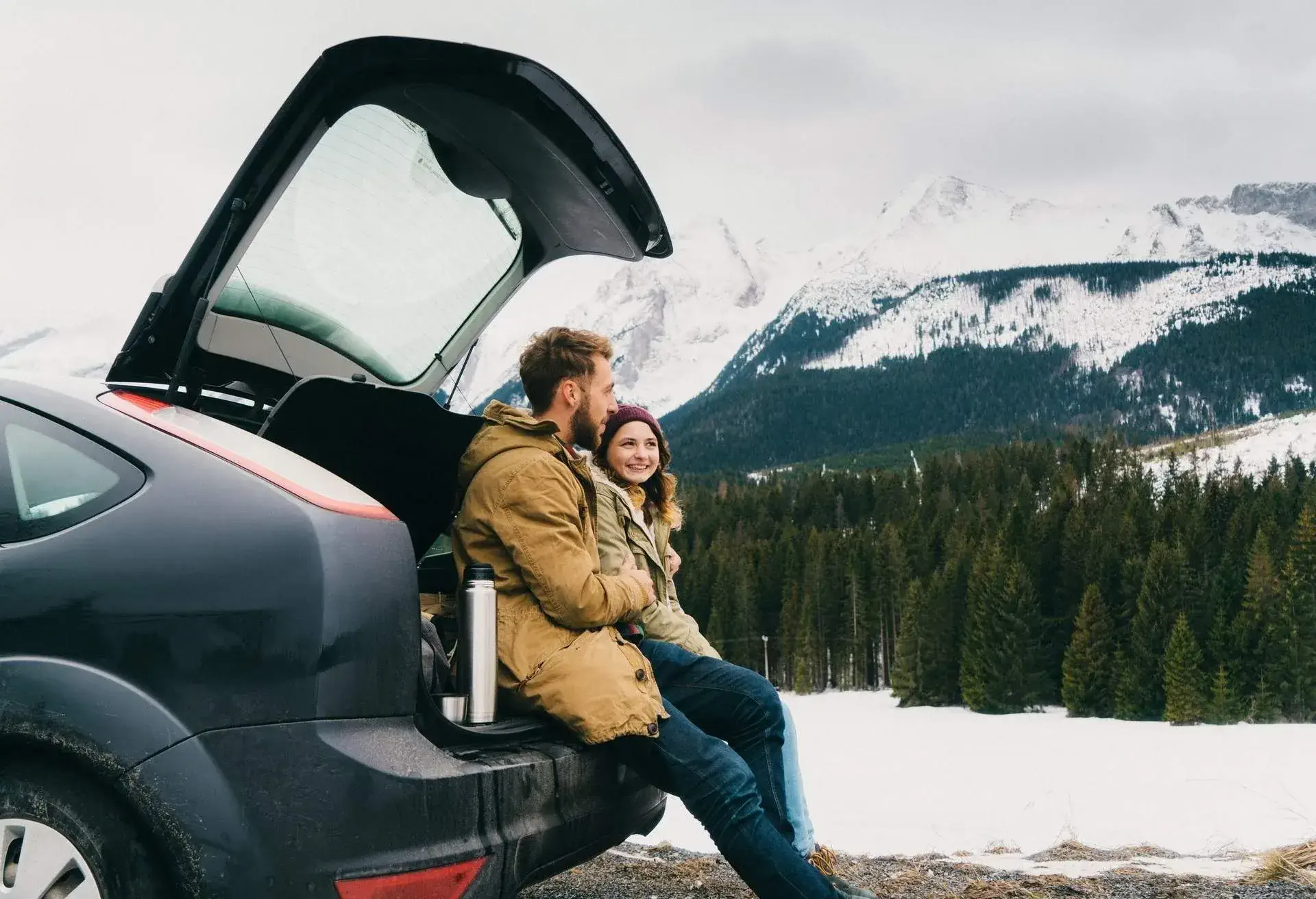 A man and a woman seating on the back of a car