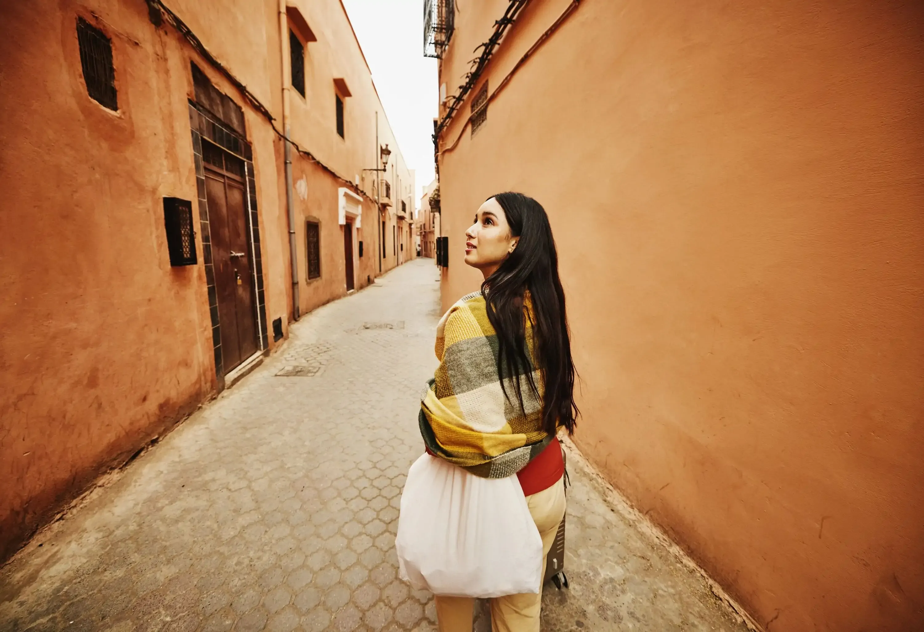 Wide shot of female solo traveler exploring the streets of the Medina of Marrakech while on vacation