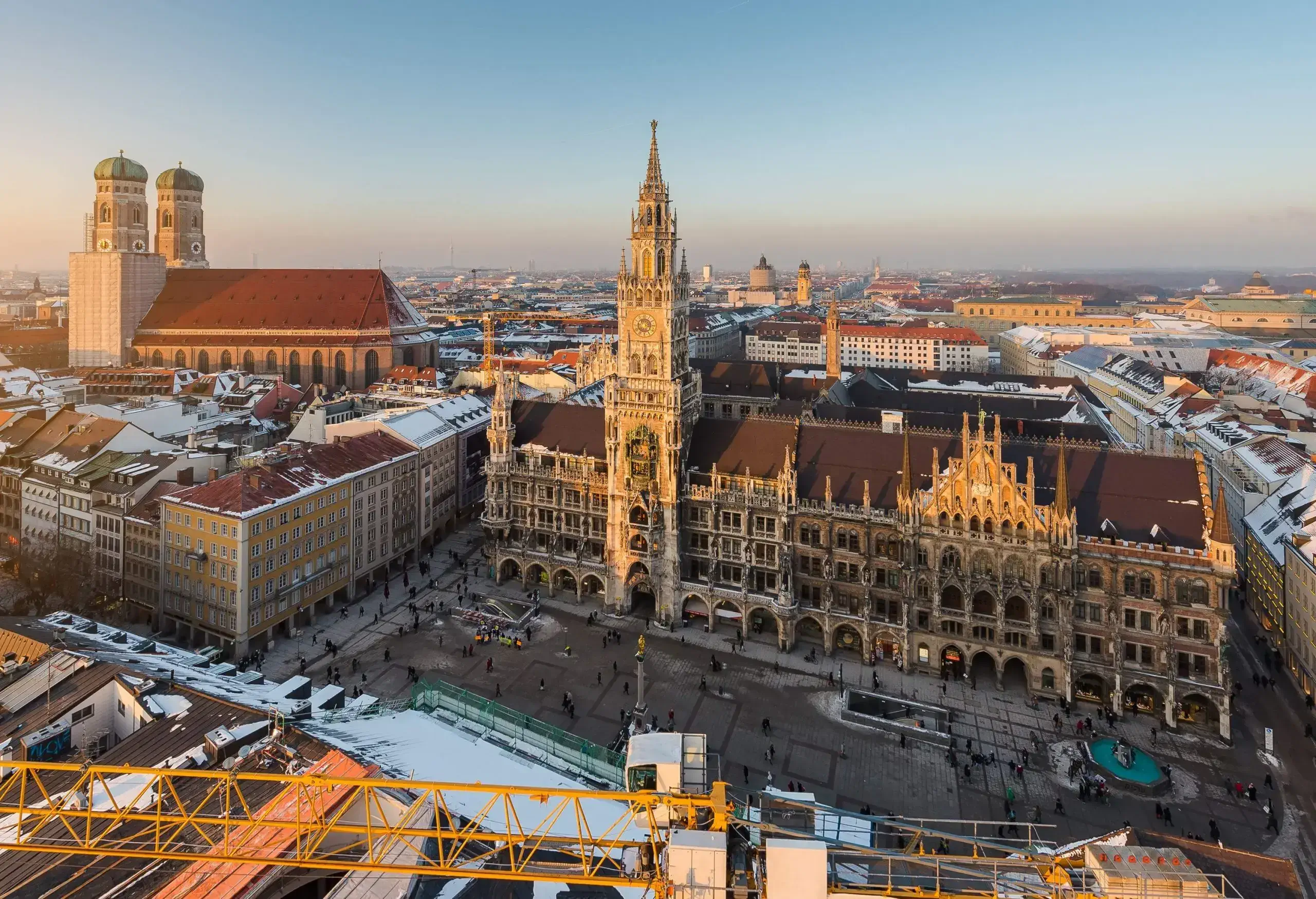An ornate gothic town hall with a spectacular tower facing the city's main square in the middle of compact tall buildings.