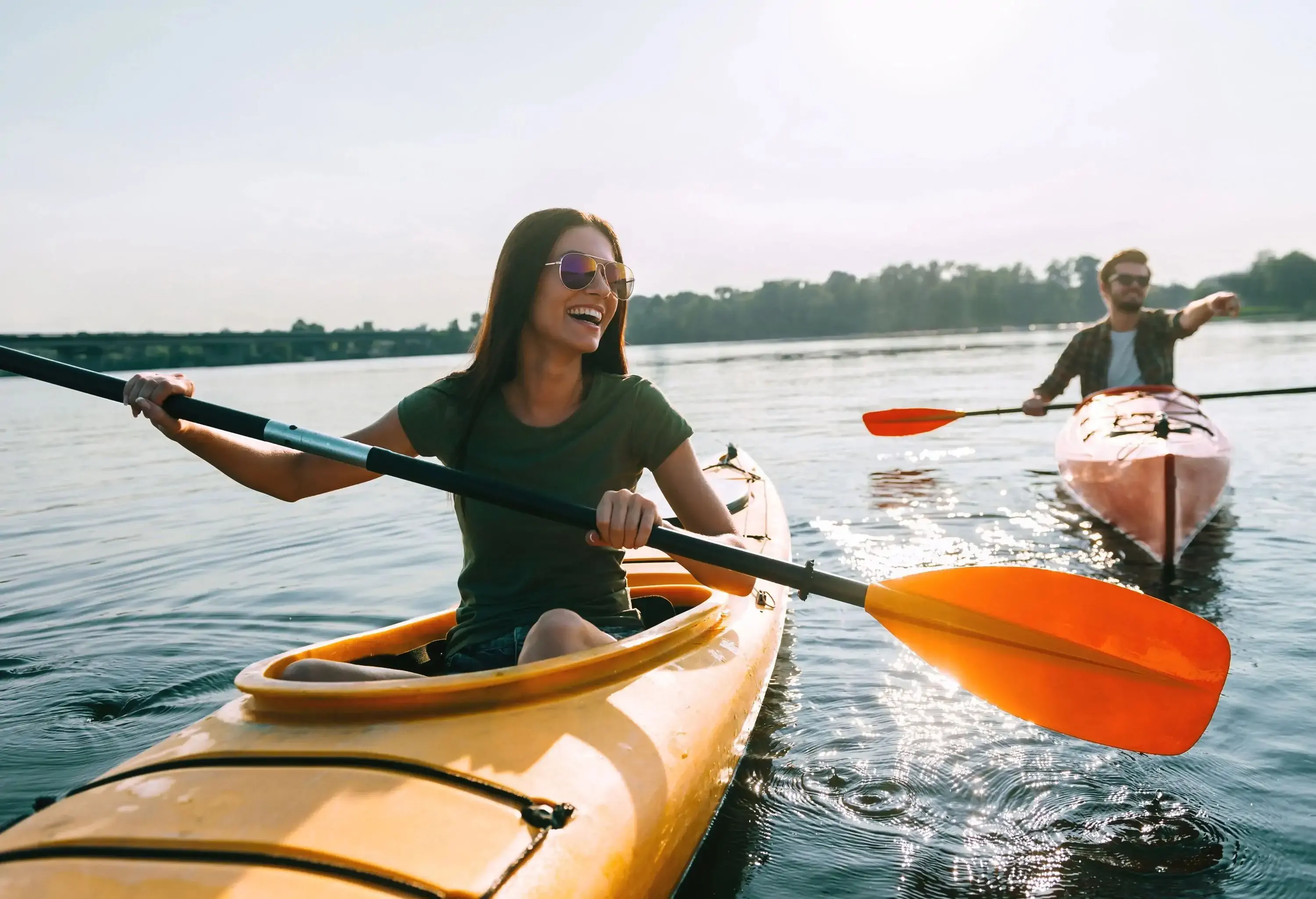 A man and a woman having fun kayaking on a lake.
