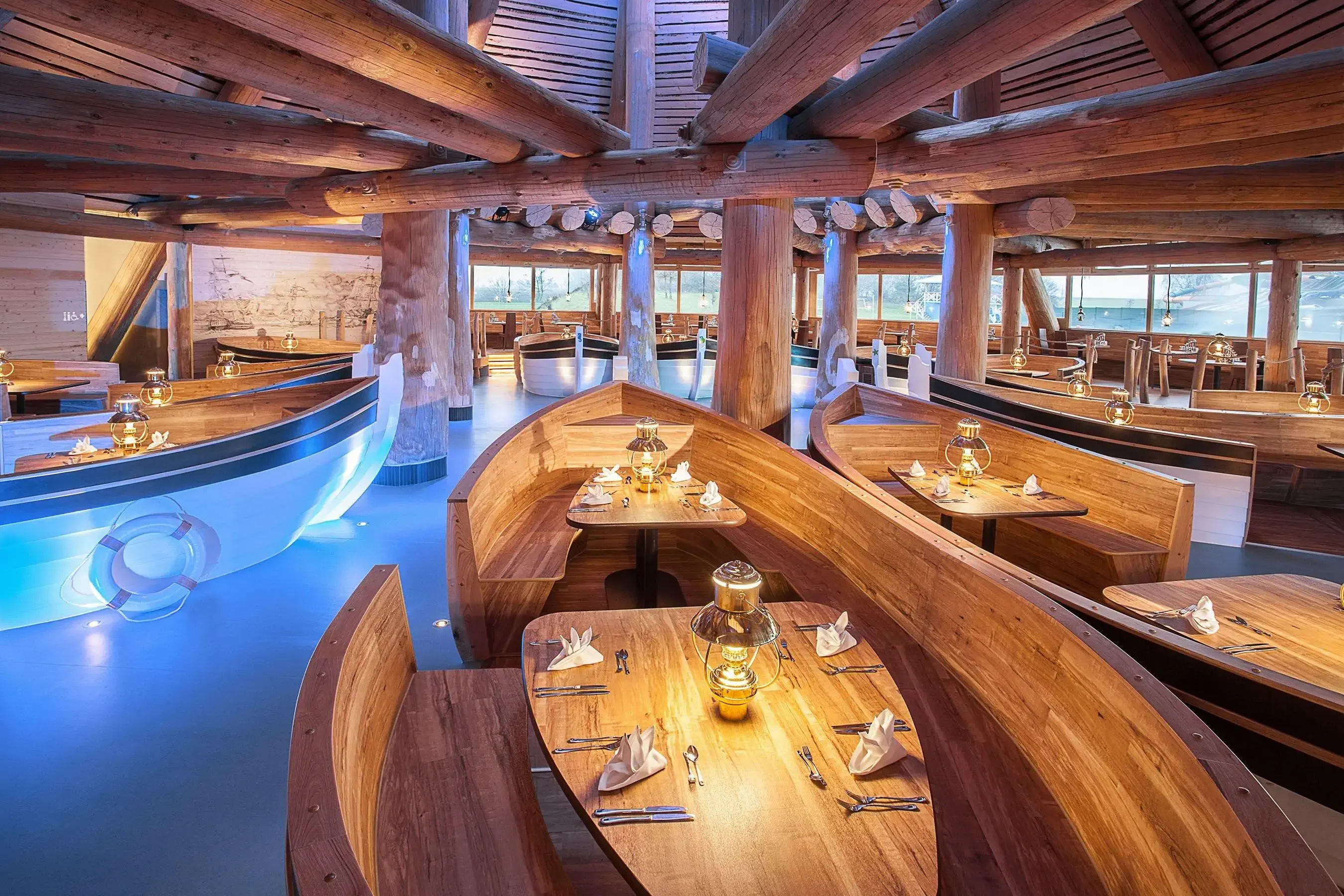 A cozy restaurant featuring wooden tables and benches shaped like boats
