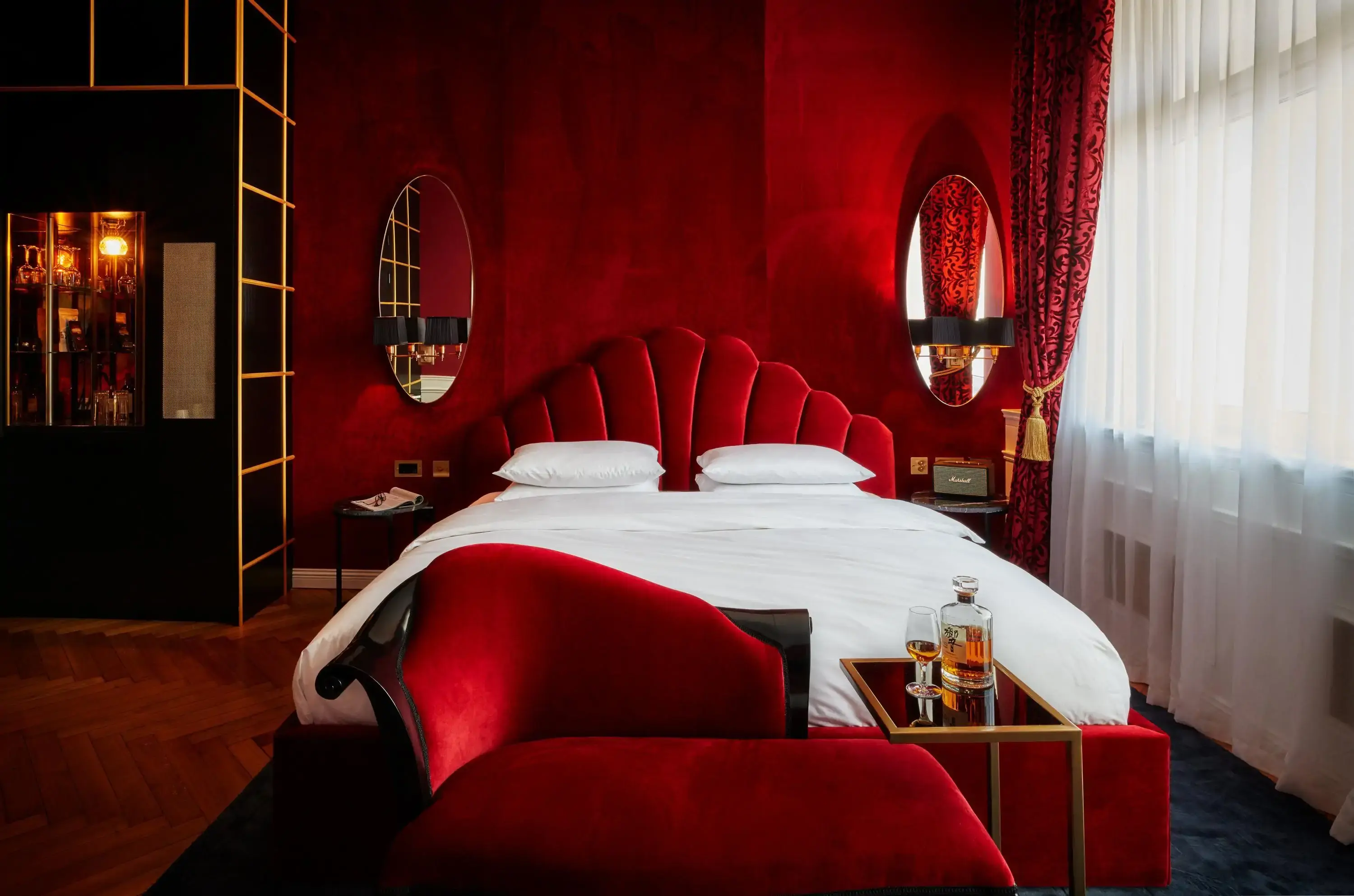 A bold and luxurious hotel room featuring rich red velvet decor