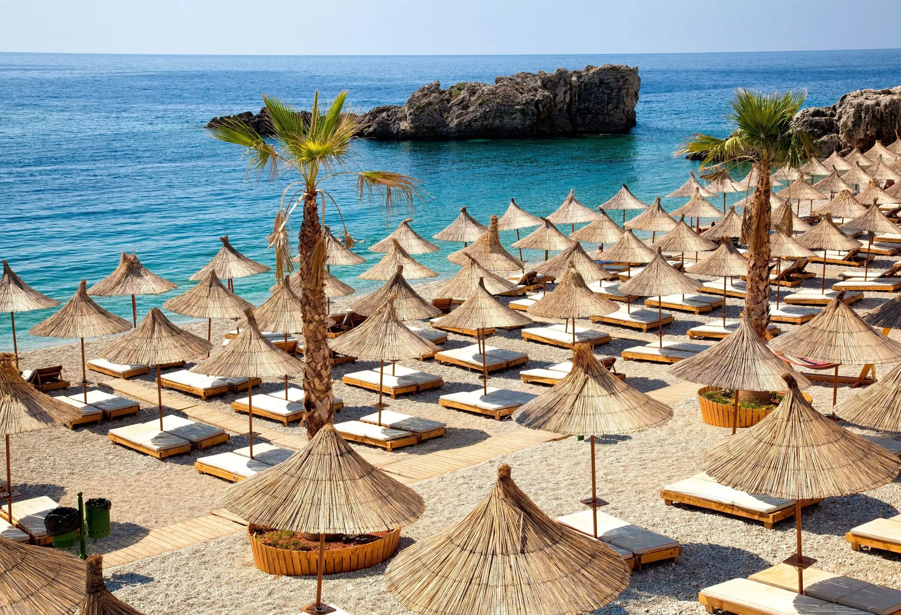Rows of hay parasols on a mediterranean empty beach