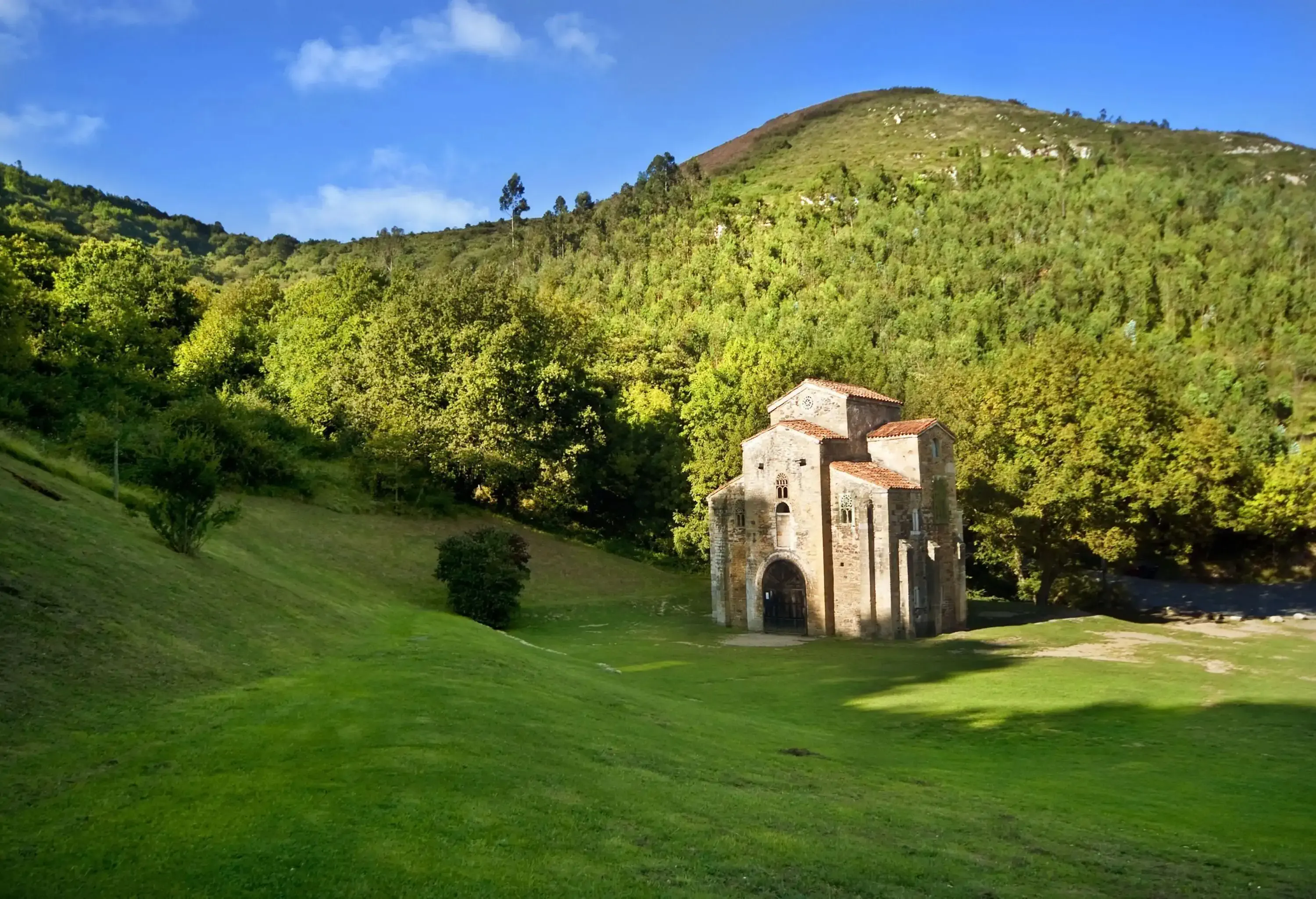 Old medieval church surrounded by green hills on a sunny day