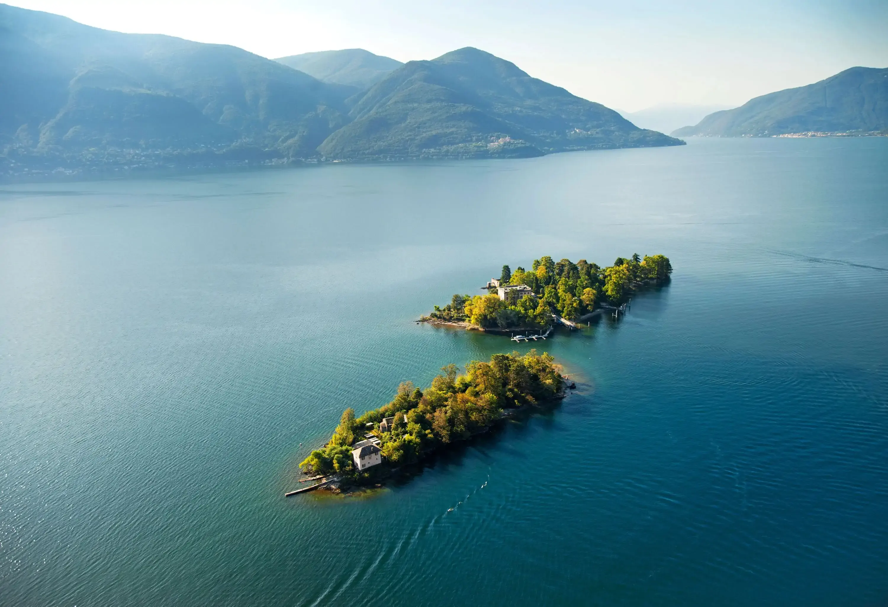 Aerial view of two small green islands on a lake surrounded by mountains