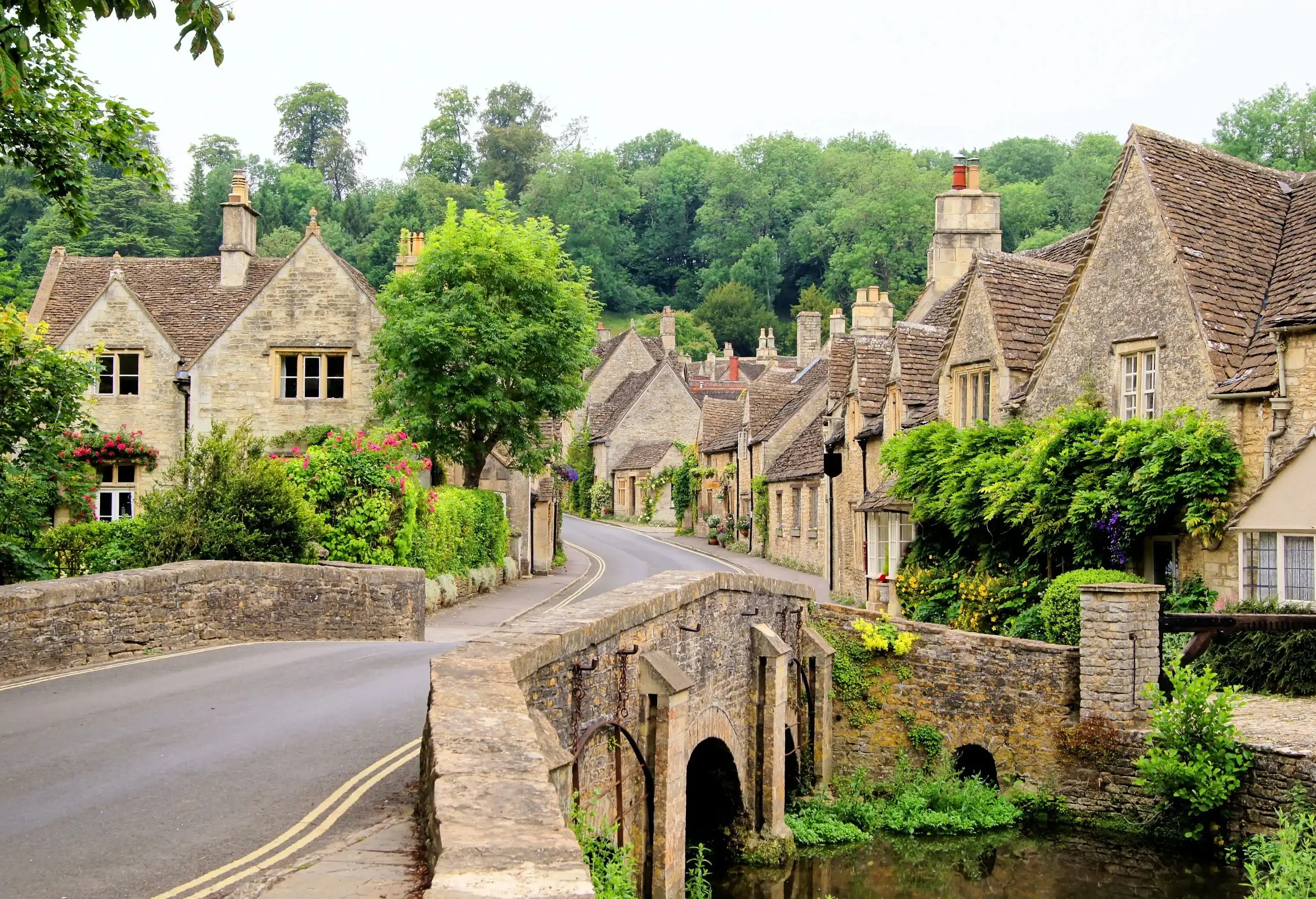 A road bridge across a river that leads to the stone houses in a village.