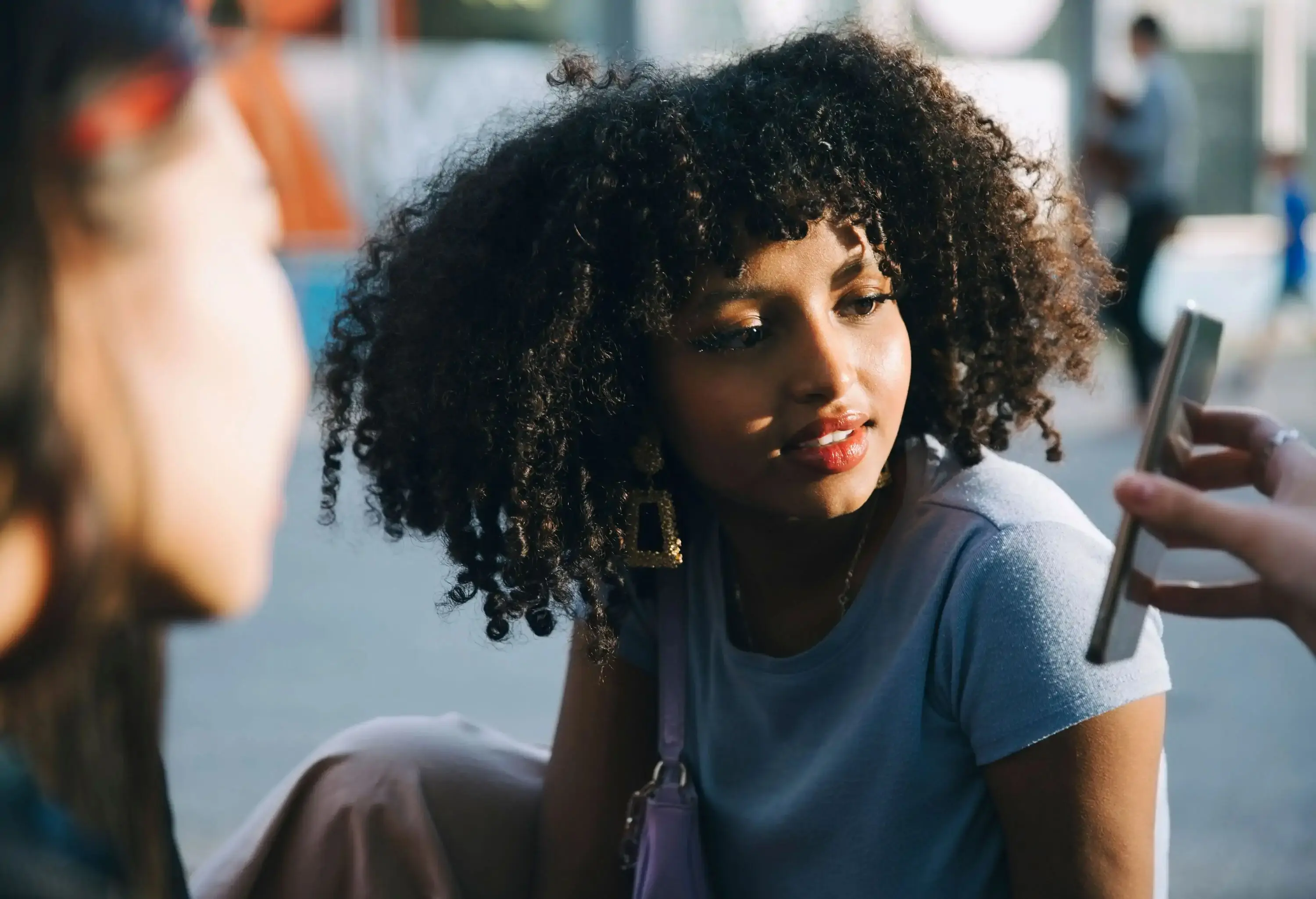 Young woman looking at smartphone from a a friend's hand