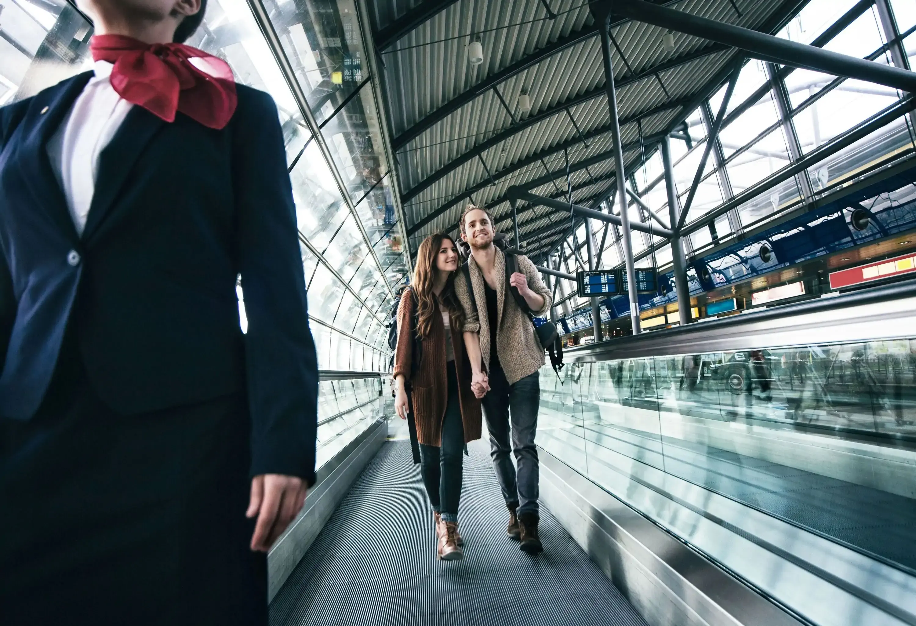 Young backpacker couple on man conveyor at the airport