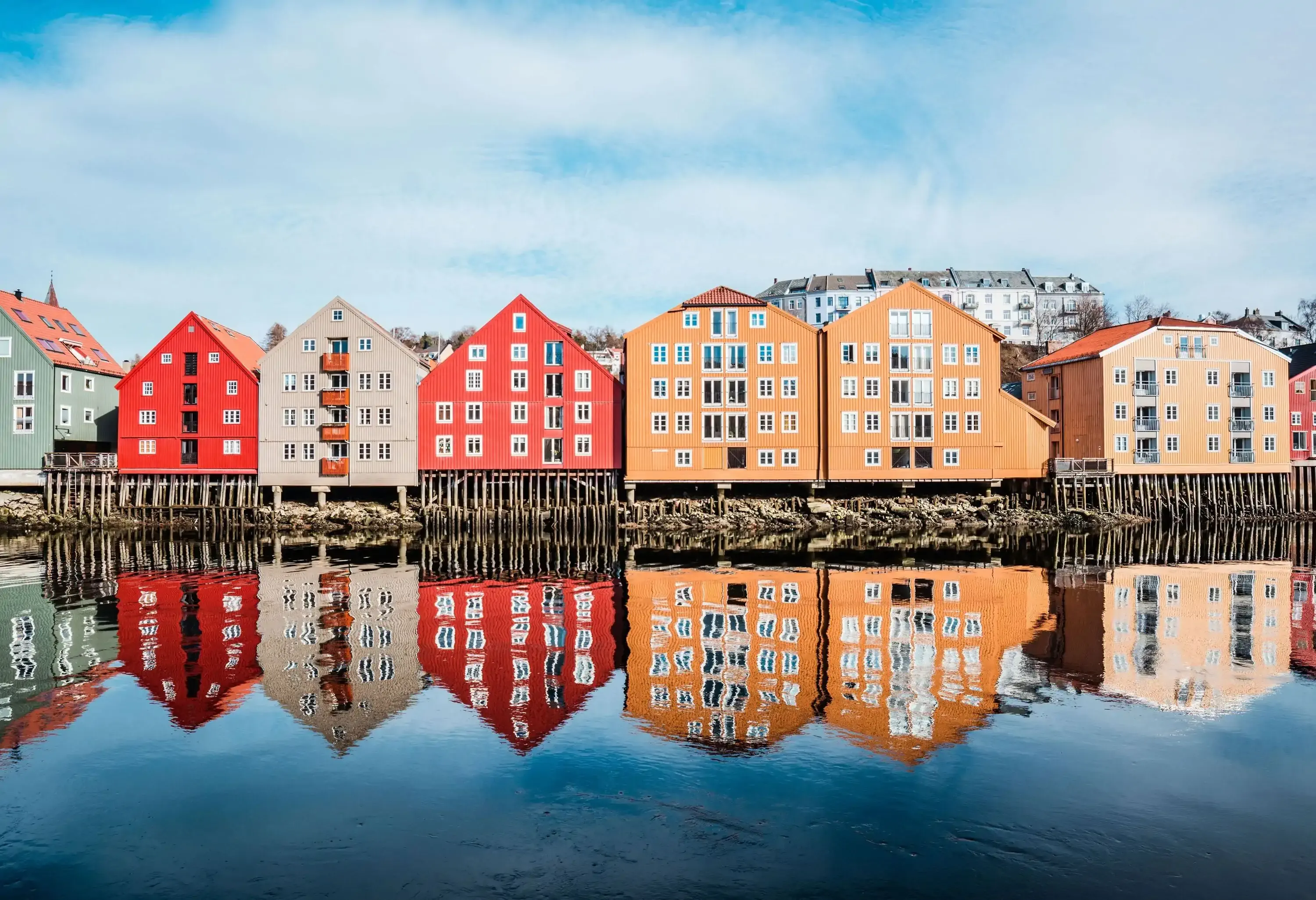 A row of colourful buildings reflected on the glassy water's surface.