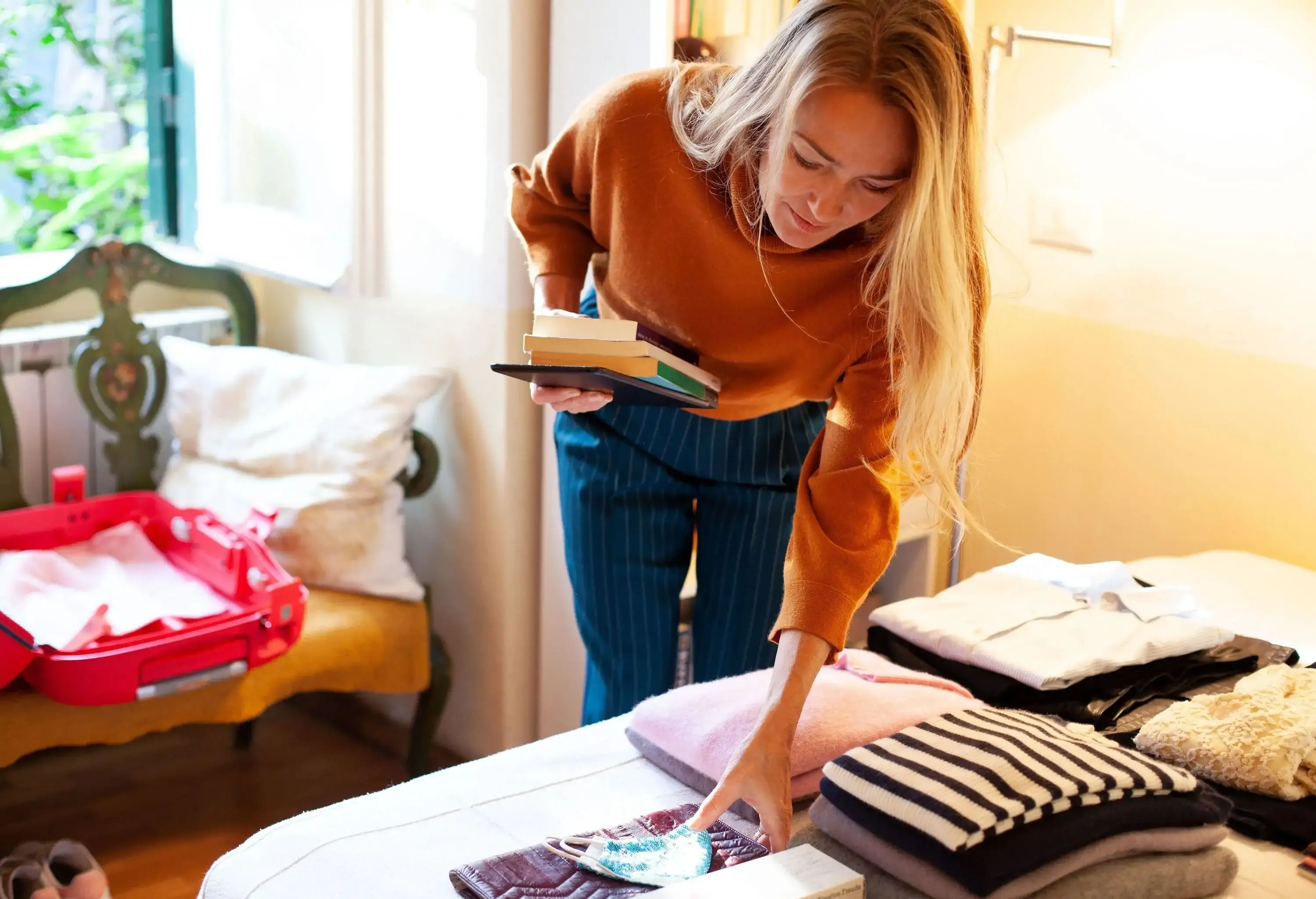 A busy blonde-haired woman packs up her suitcase.