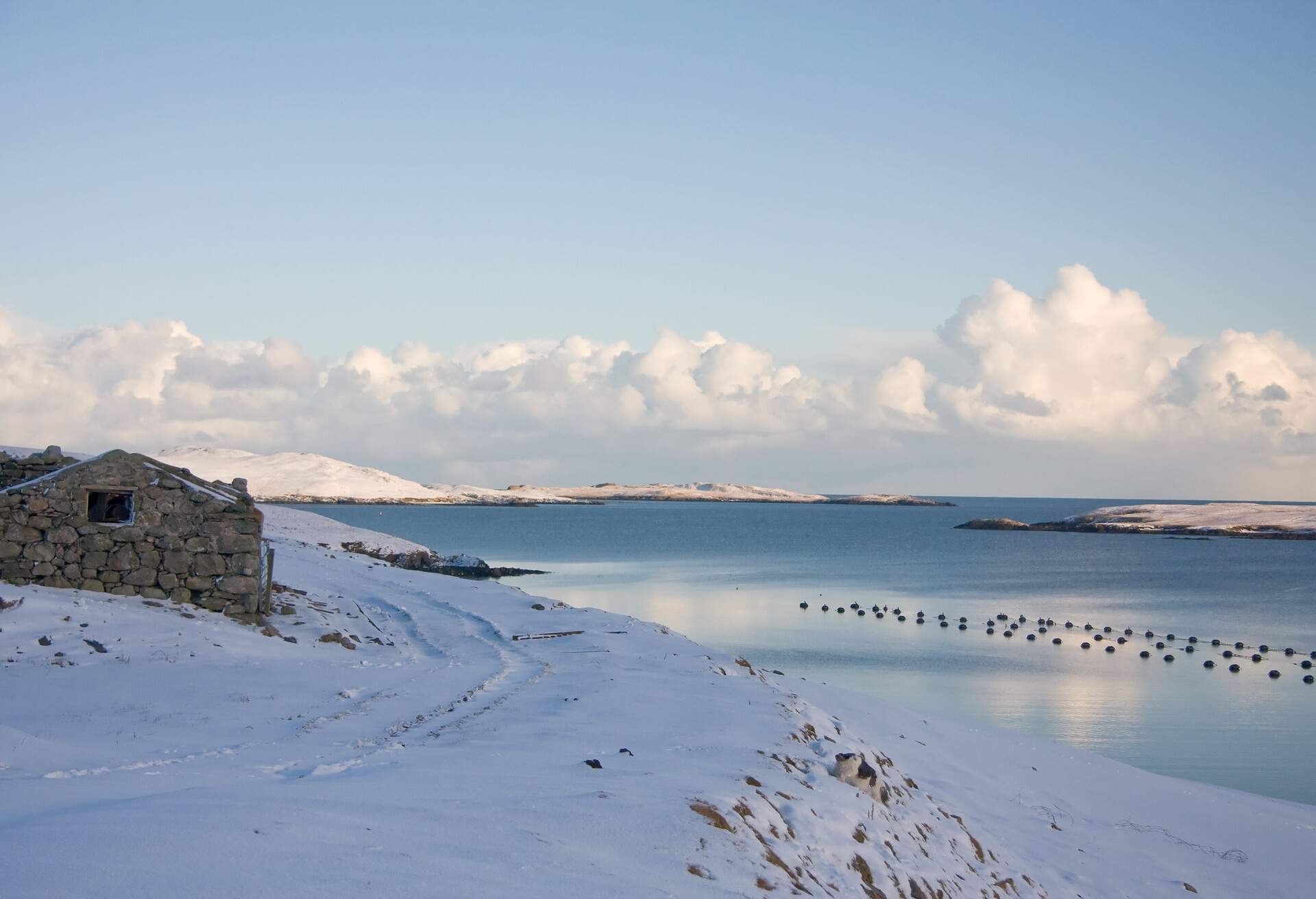 A croft house on a shore covered in snow.