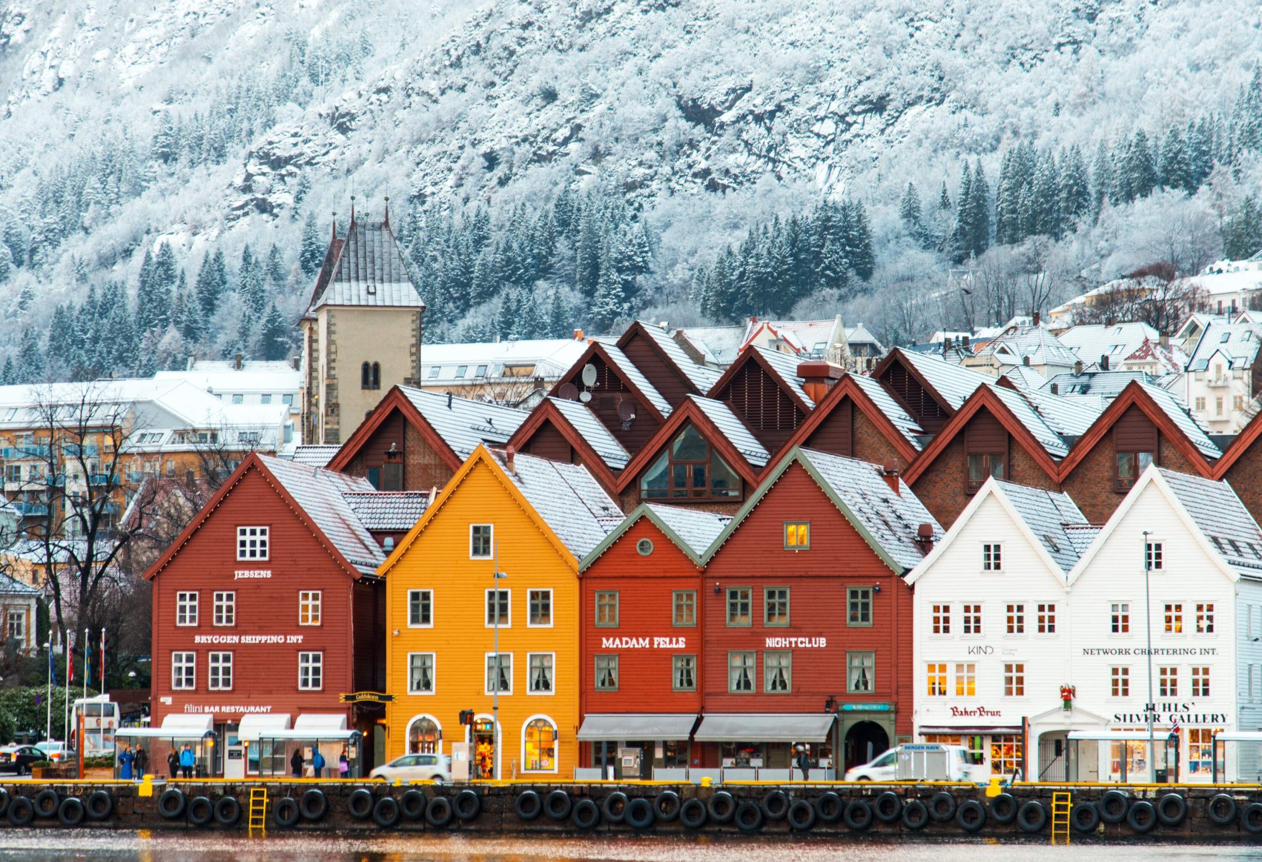 Bryggen's lovely waterfront neighbourhood, with vibrant houses set against snow-covered mountains and frosted trees.