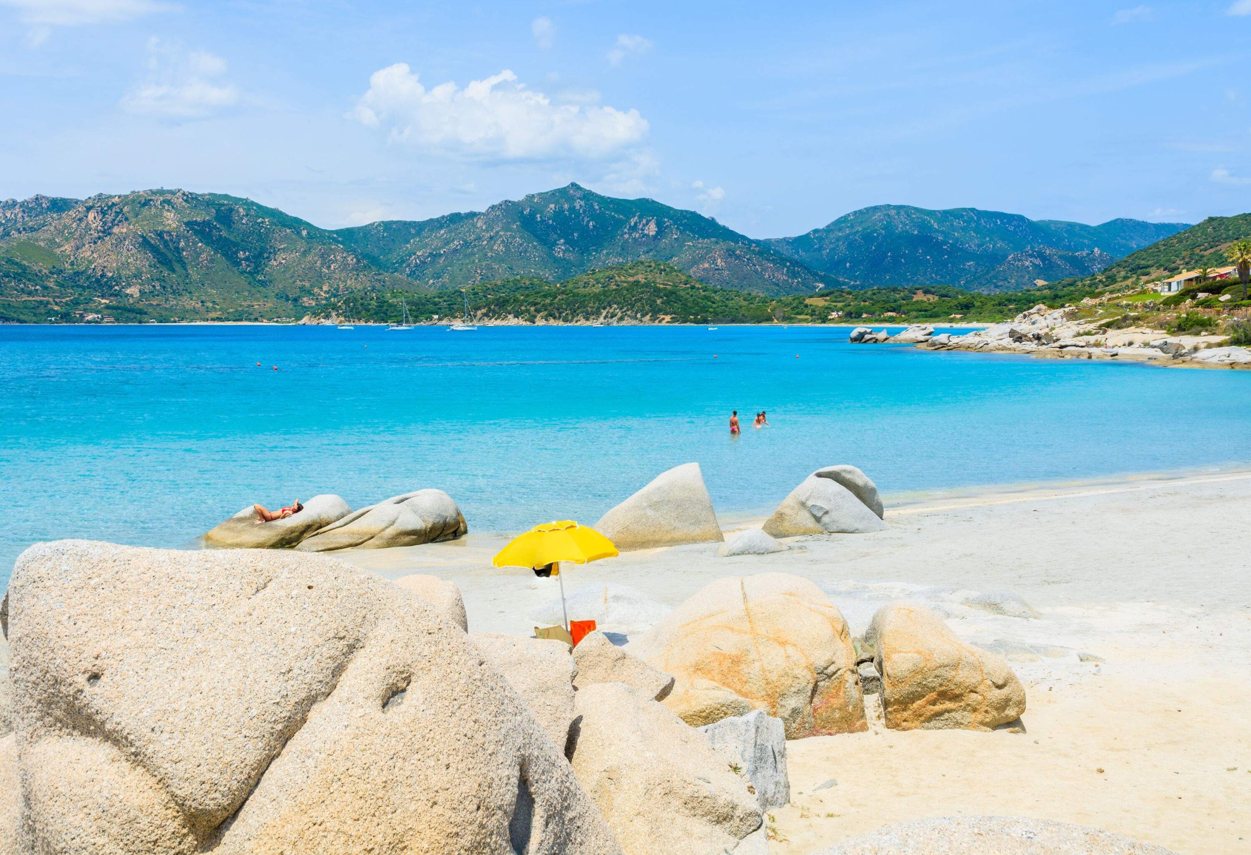Some visitors enjoy the crystal-clear turquoise water and rock boulders along the white sand beach.