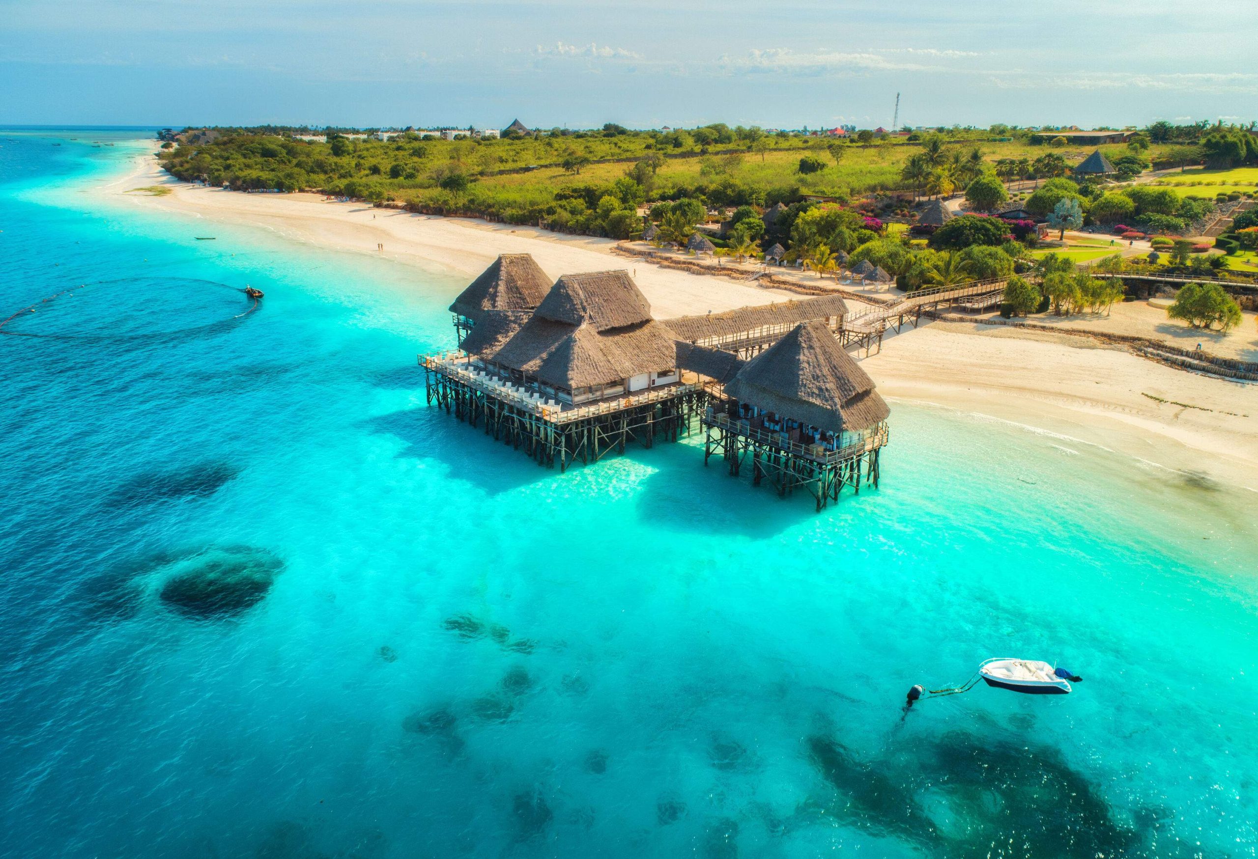 Aerial view of a luxury beach resort with turquoise sea water and a lush shore.