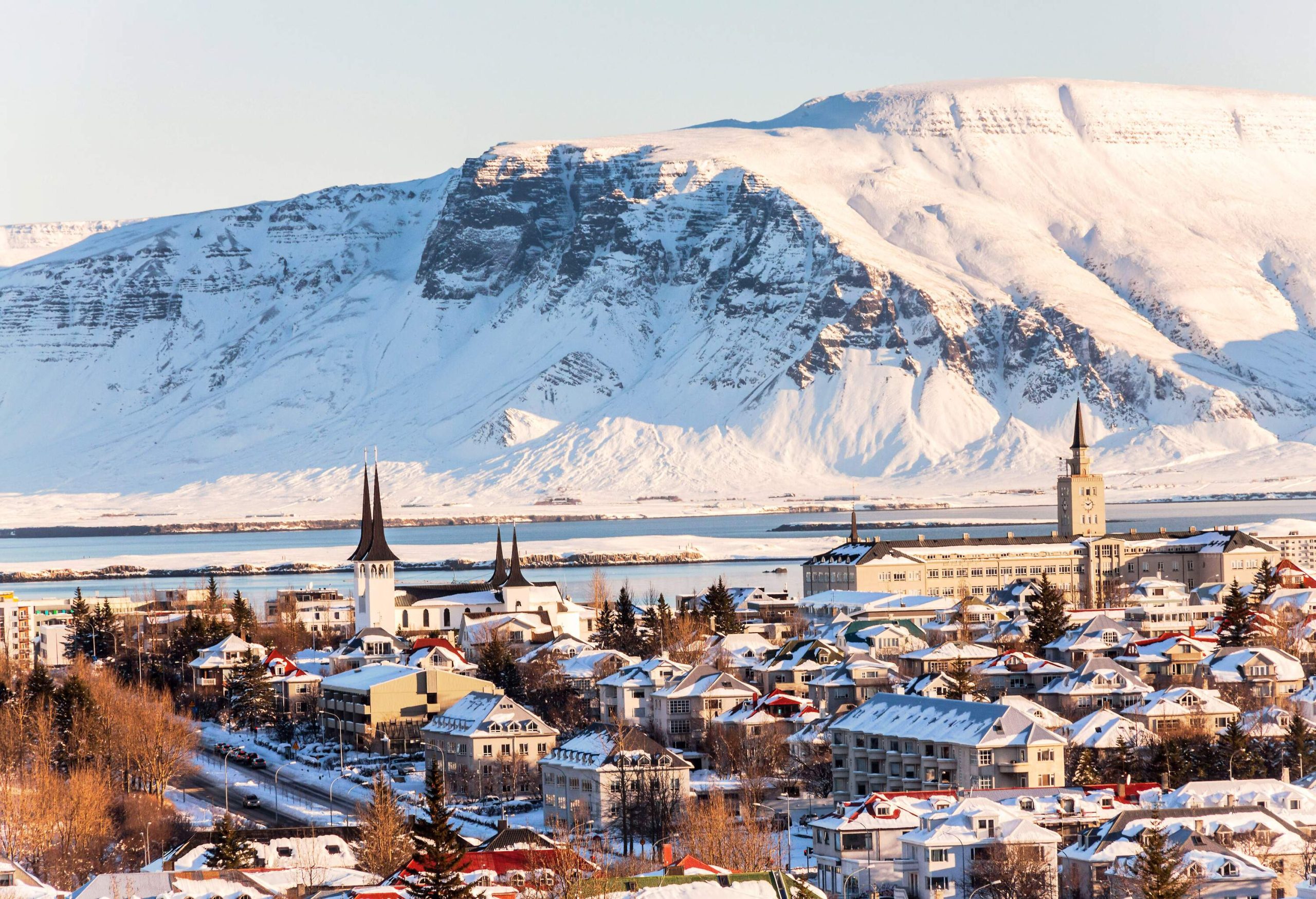 Impressive church spires rising above a cityscape with a snow-capped mountain in the distance.