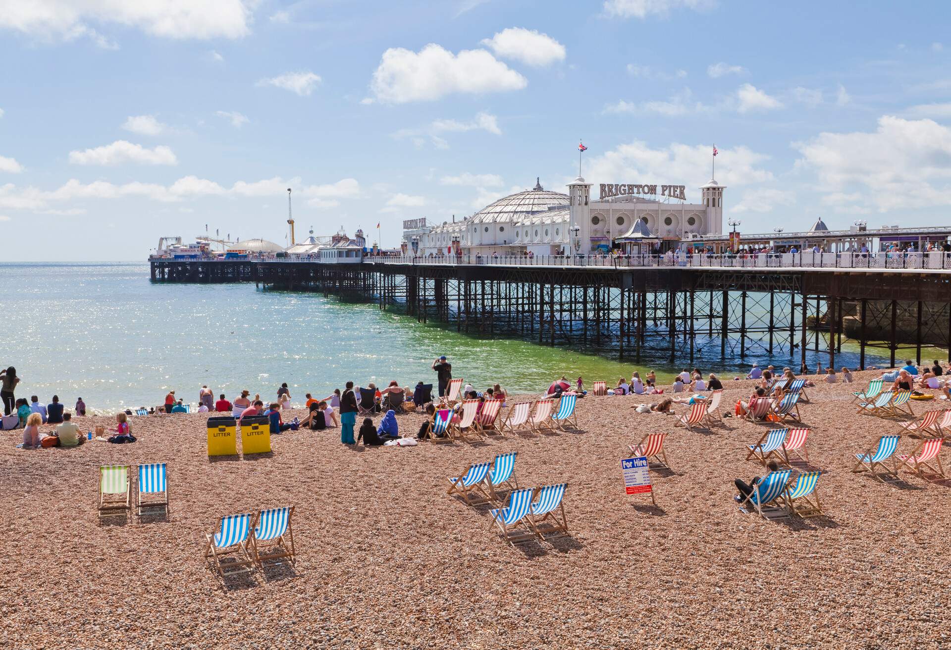 People hanging out on the pebbly beach at Brighton Pier.