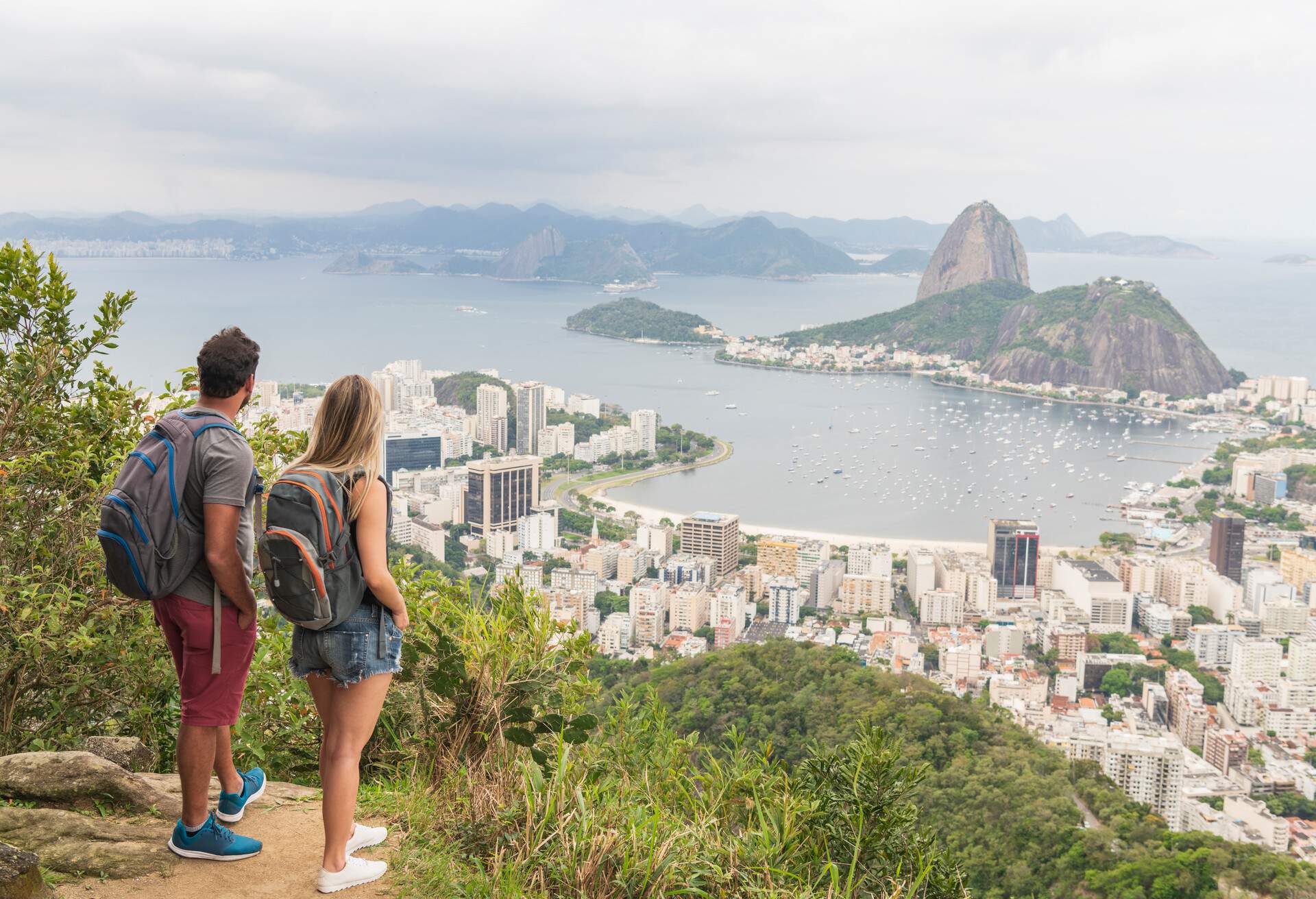 Backpacking tourists standing with views of Sugar Loaf Mountain in Rio de Janeiro