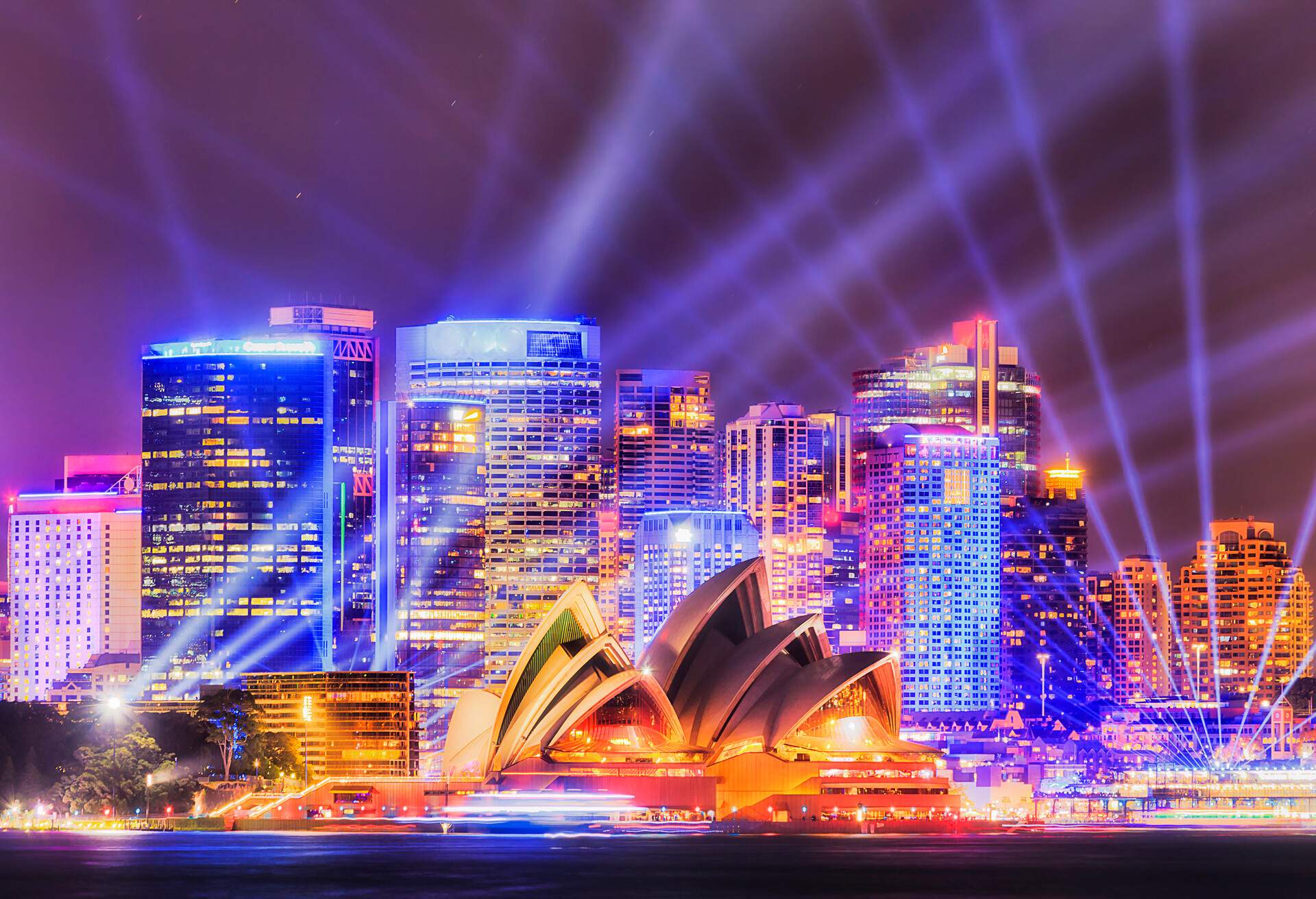 The Sydney Harbour skyline, including the Sydney Opera House , bathing in a kaleidoscope of brilliant night lights.