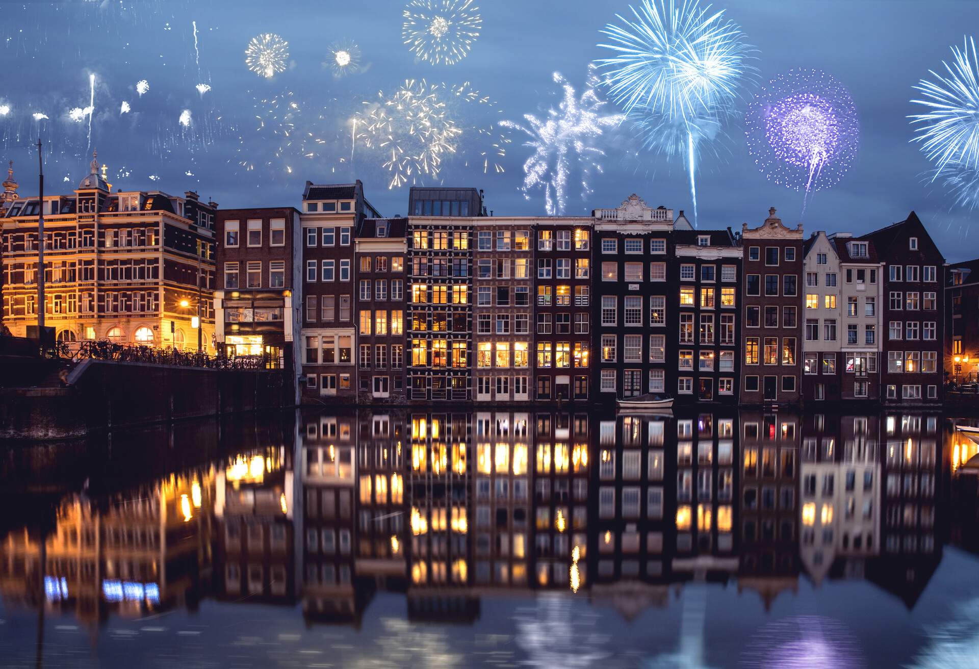 Fireworks bursting in the night sky above the canal-side buildings.