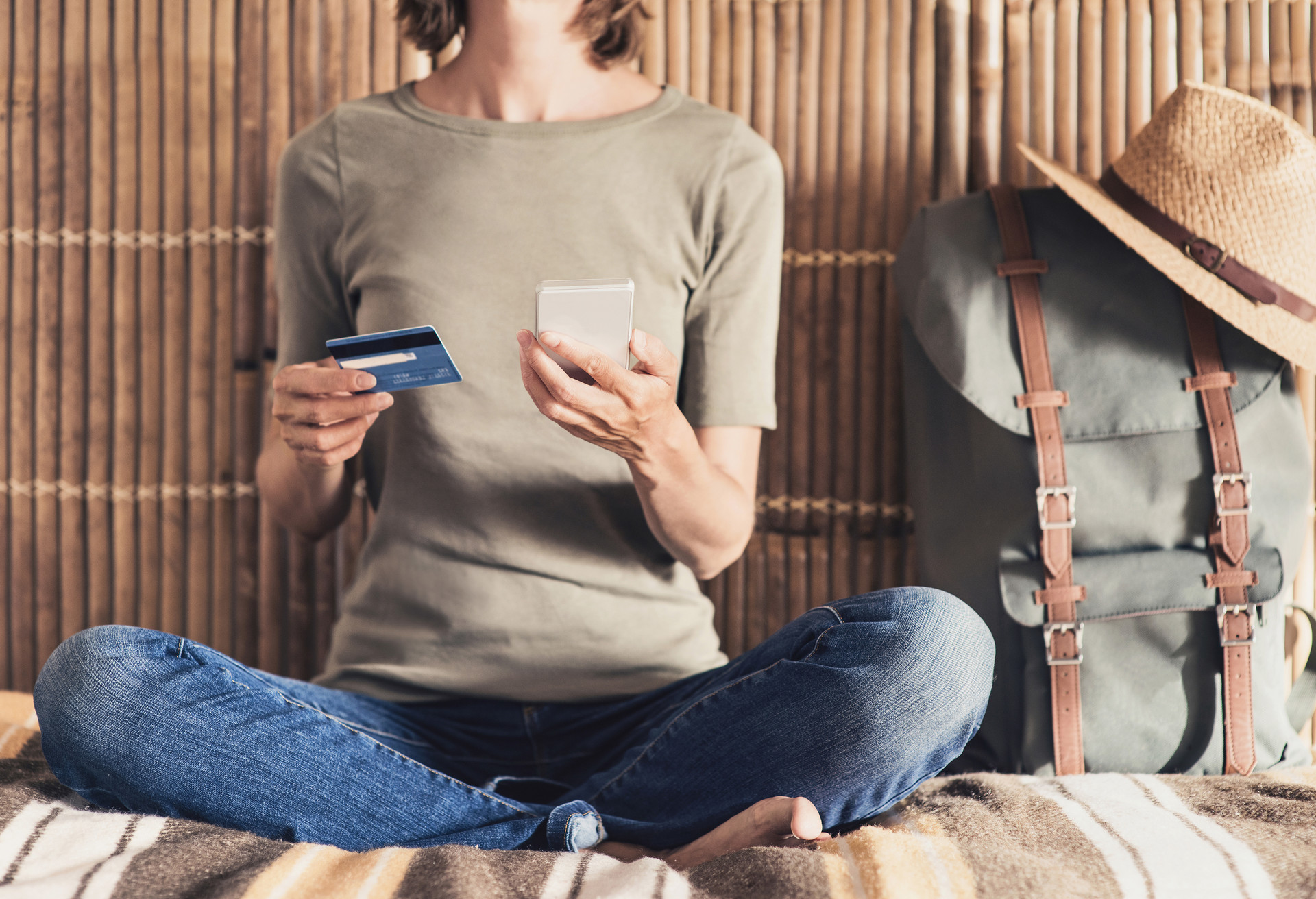 Young woman on vacations using phone and credit card. Online shopping concept