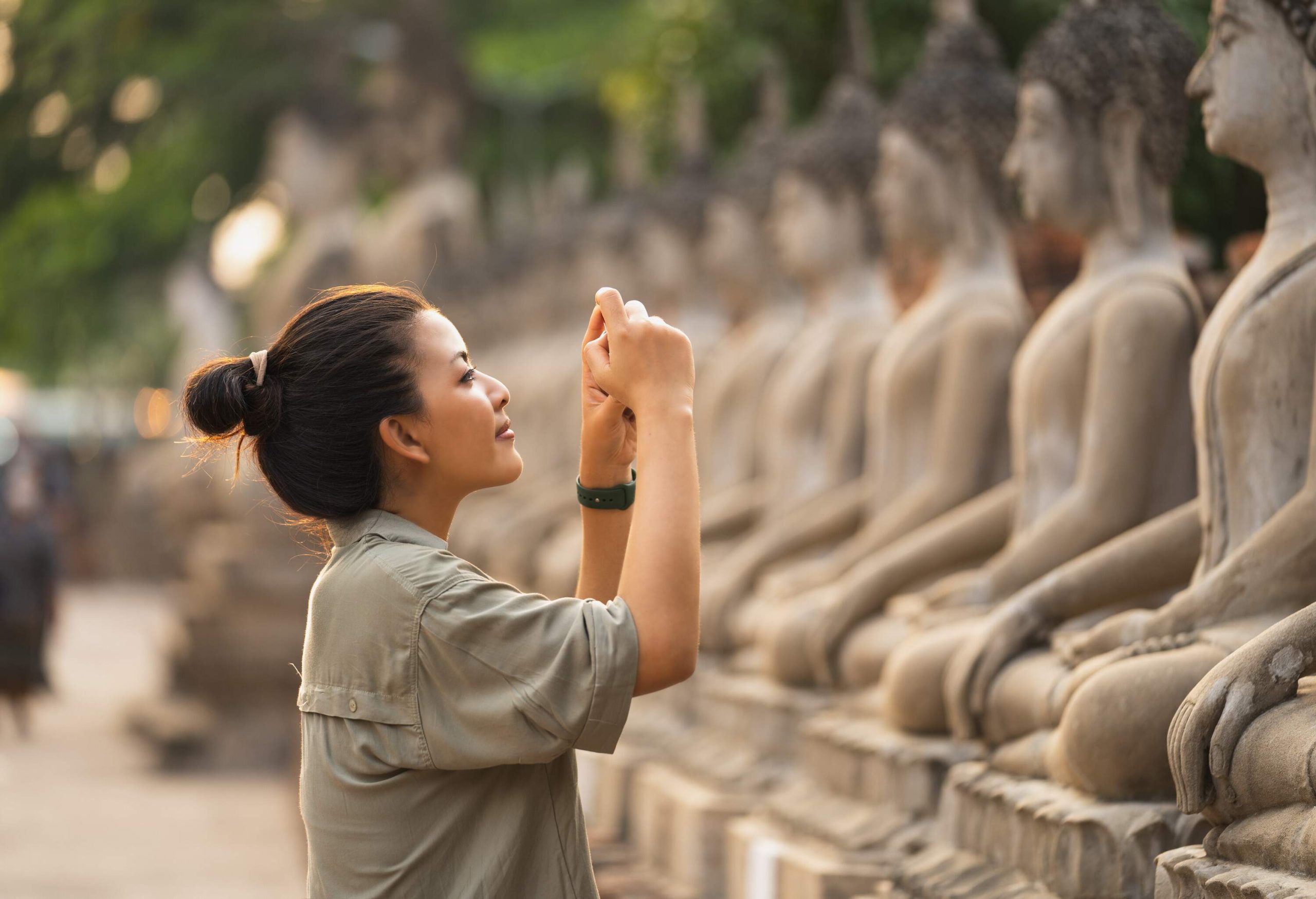 A woman taking photographs of a line of statues.