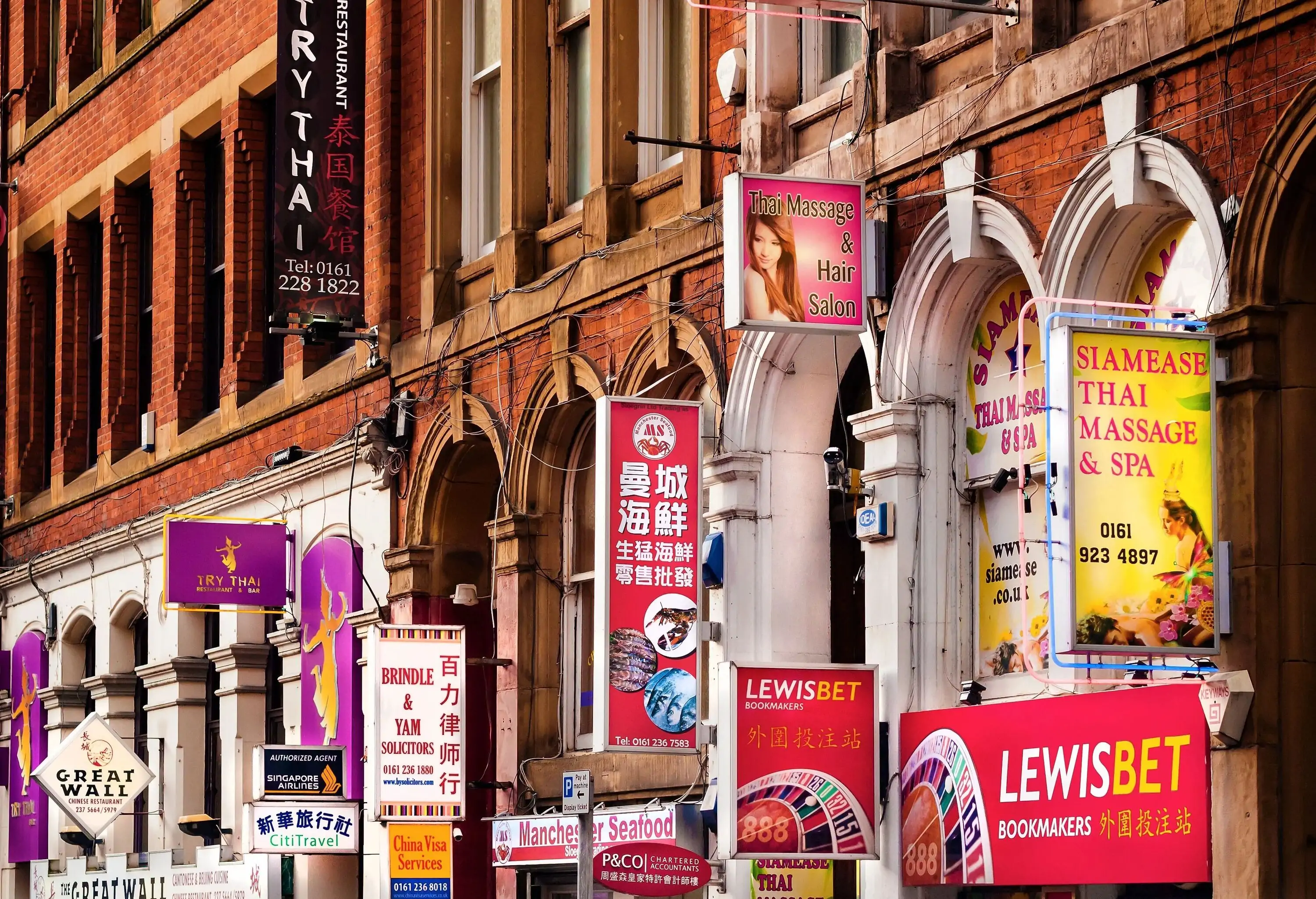A row of commercial establishments with small advertisement billboards and signages.