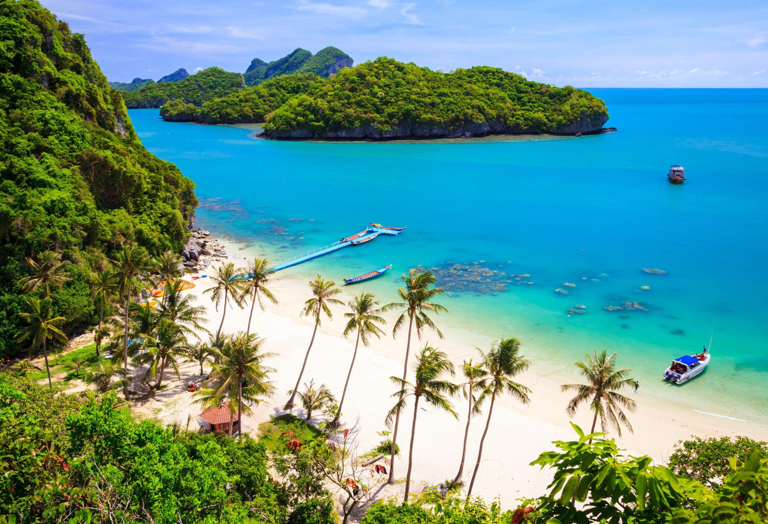 A tropical beach with lushly forested hills across its turquoise waters.