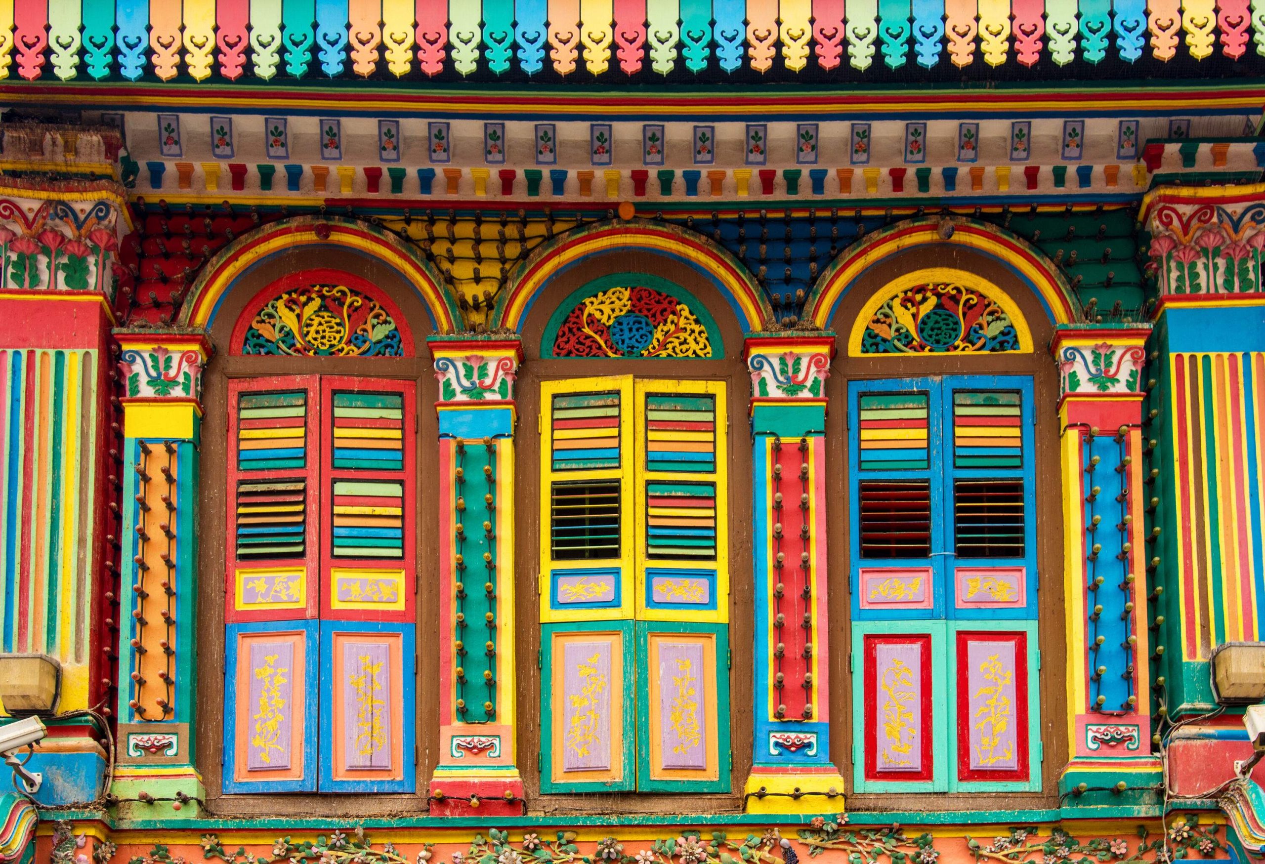 A building exhibits a vibrant, multi-coloured facade, featuring three inviting doors.
