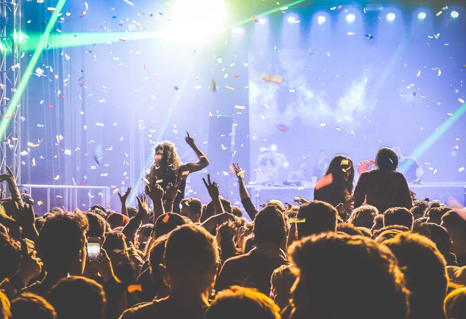 A lively concert party with an enthusiastic audience enjoying the music as colourful confetti falls from above.