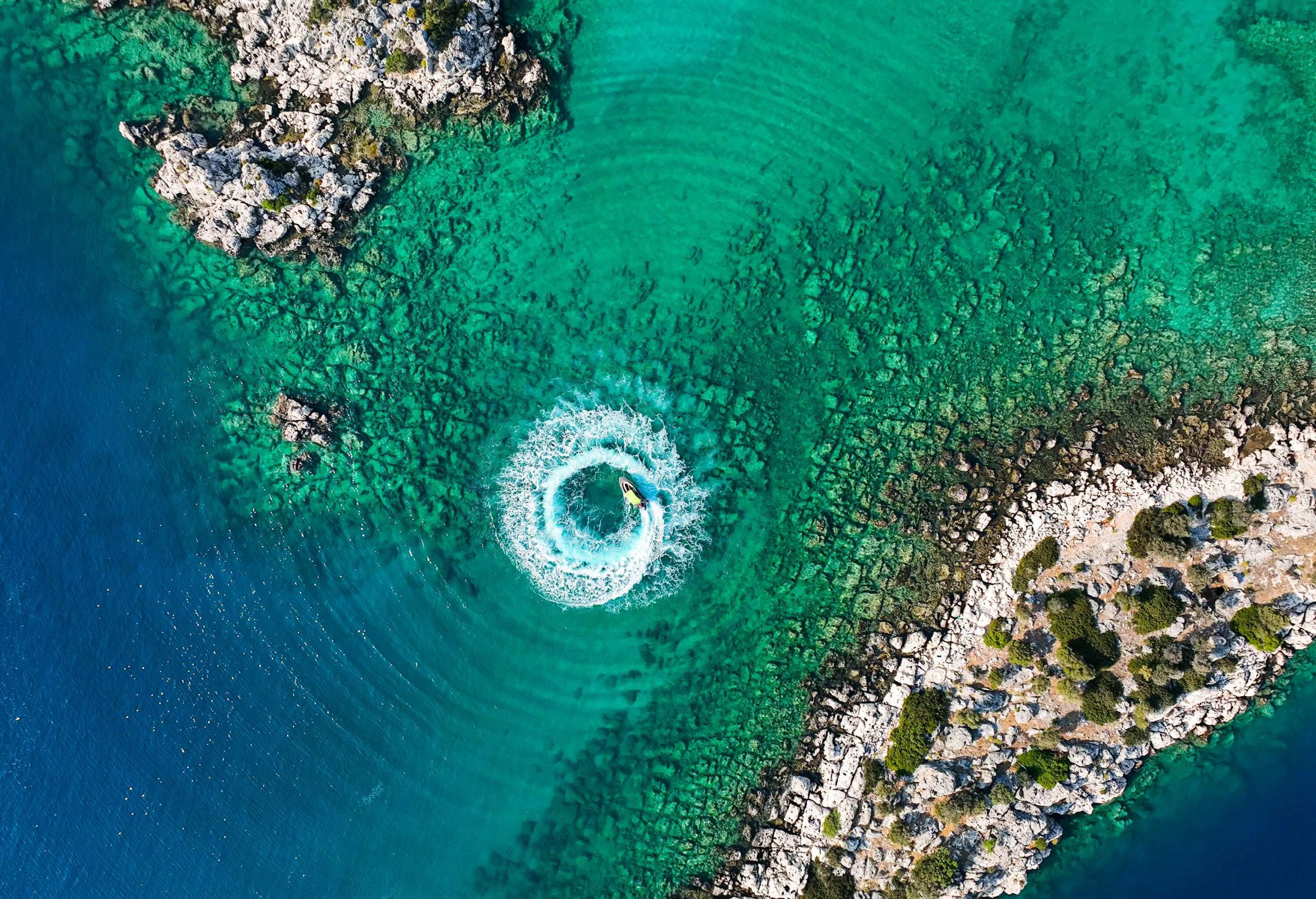 A speed boat cuts a sleek, circular path through the shimmering water.