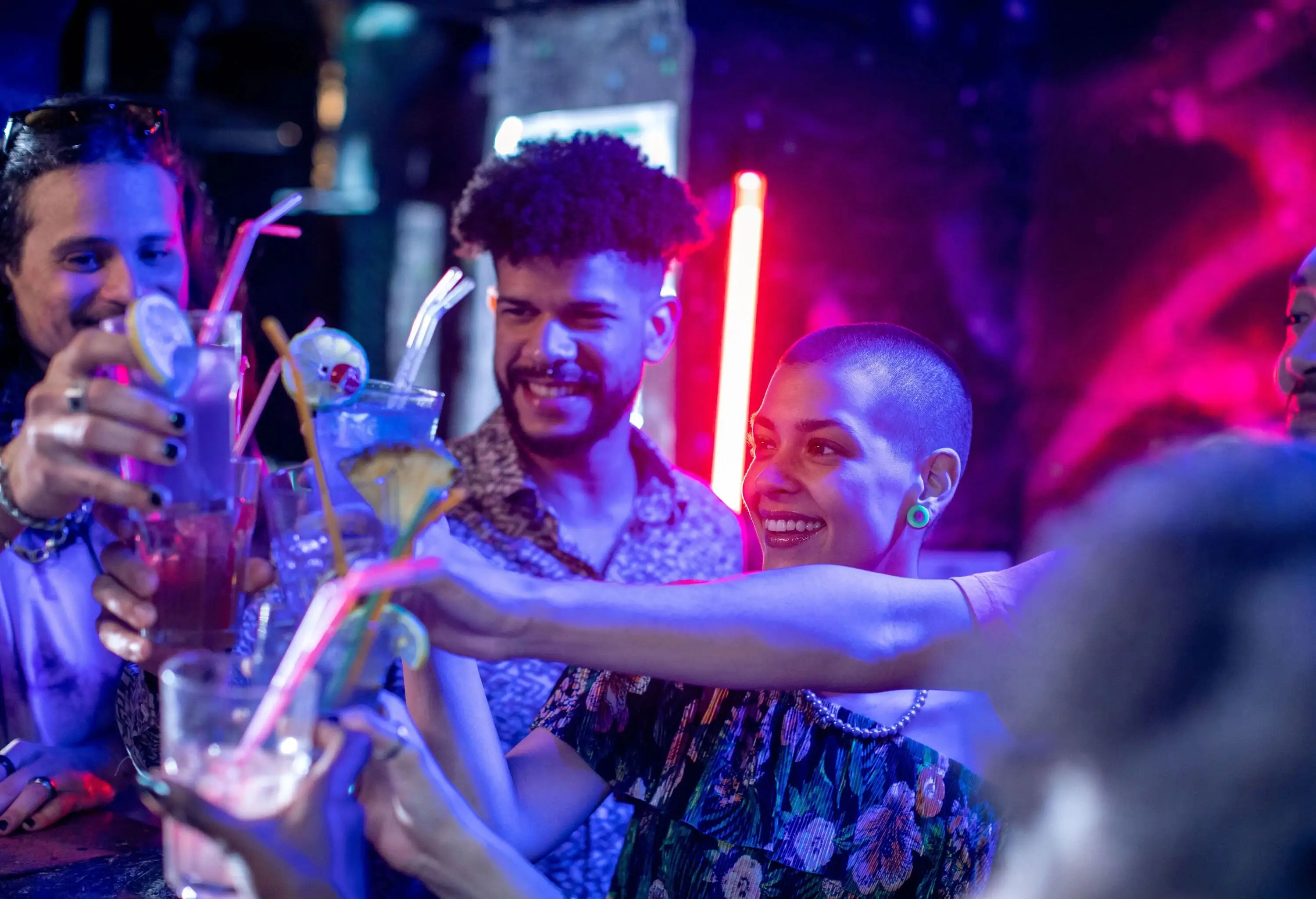 A group of male and female friends enjoying the night drinking in a bar.