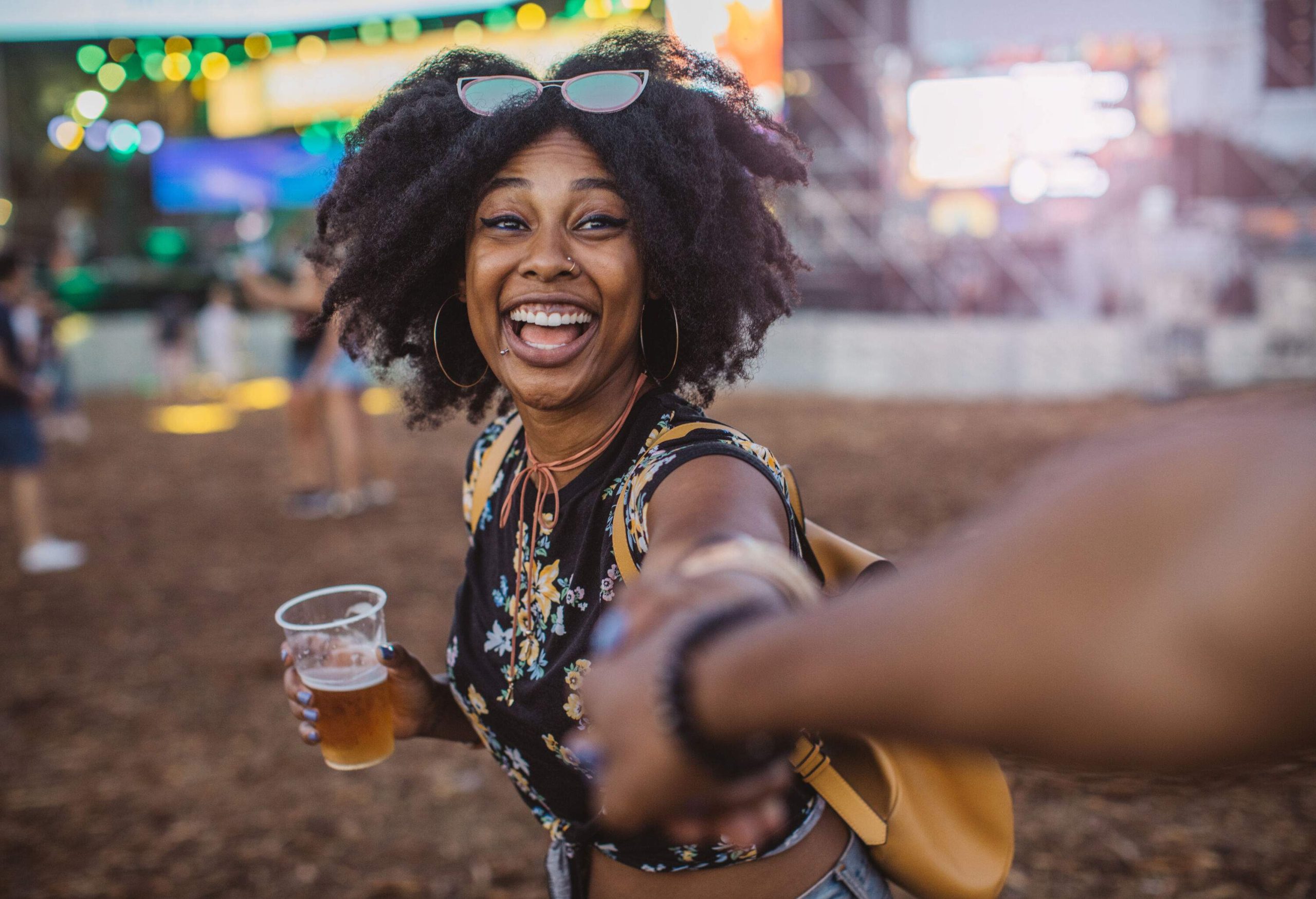 A beautiful woman with curly hair holds a glass of beer.