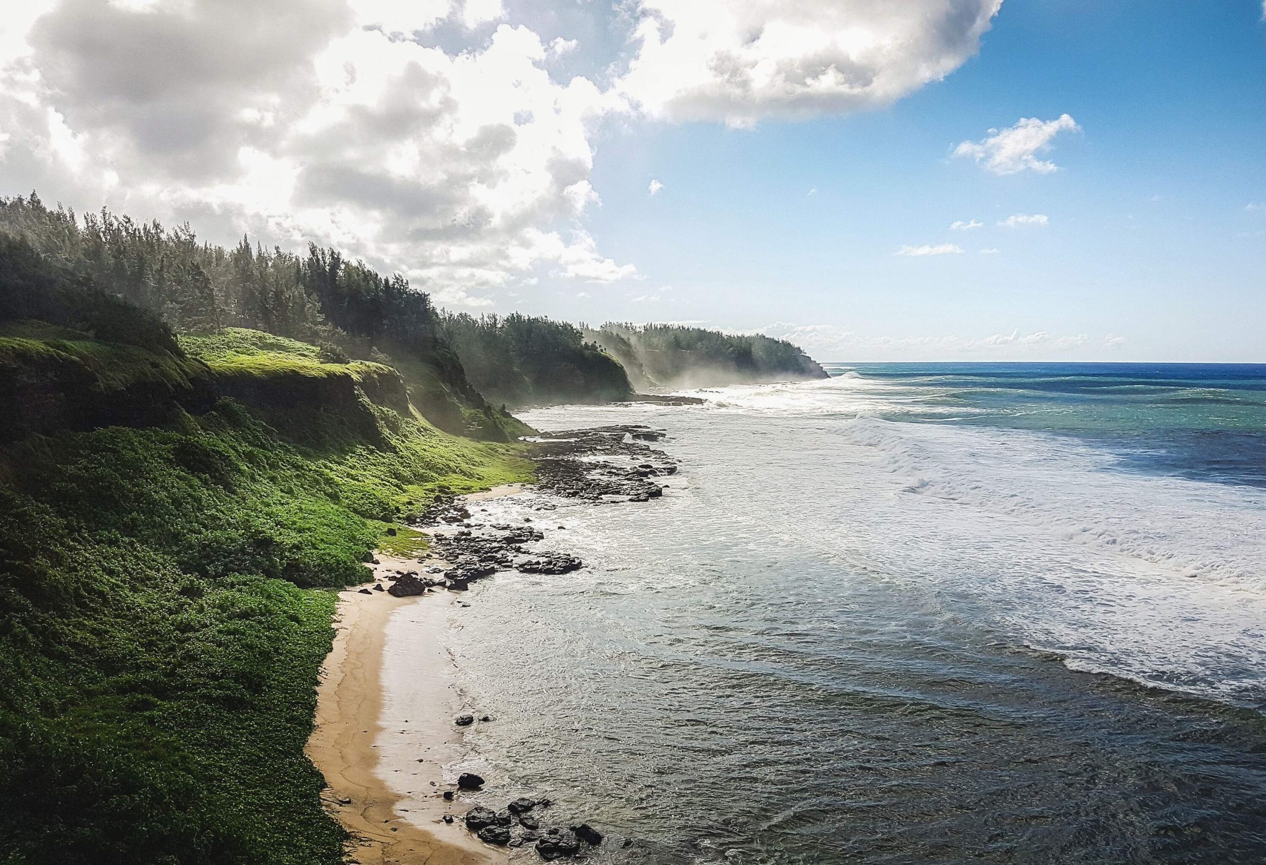 A coastline with steep slopes covered in lush vegetation along the ocean's calm waves.