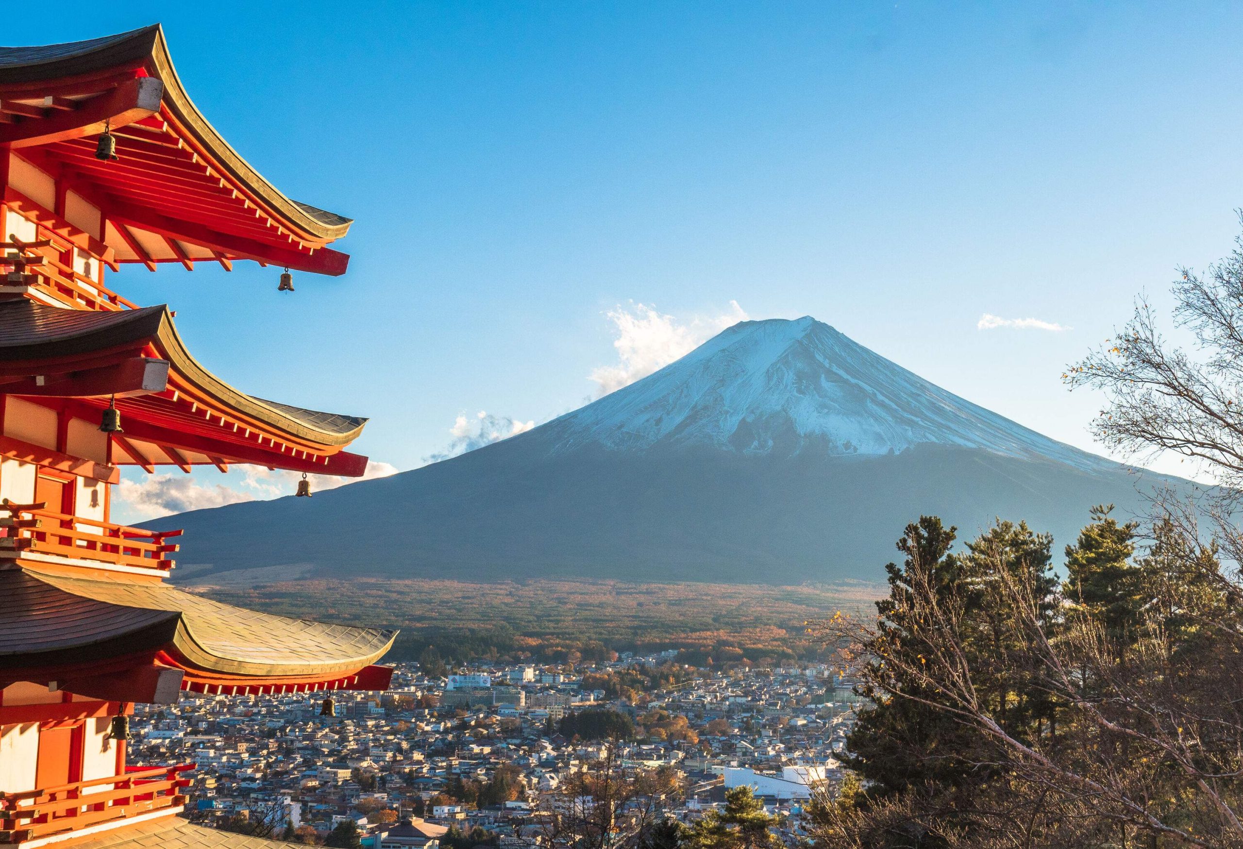 A Japanese pagoda with a view of the cityscape and snow-capped Mount Fuji.