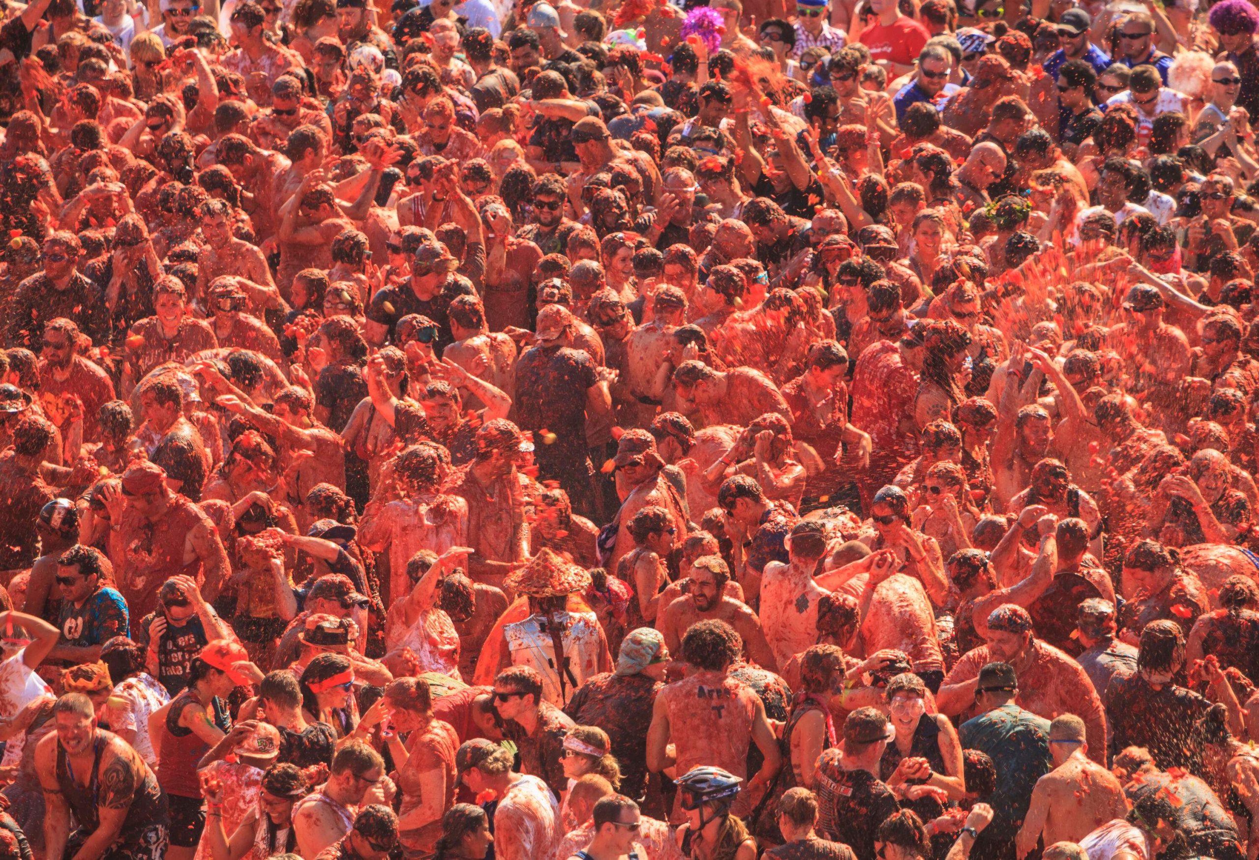A crowd of people throwing tomatoes at each other.