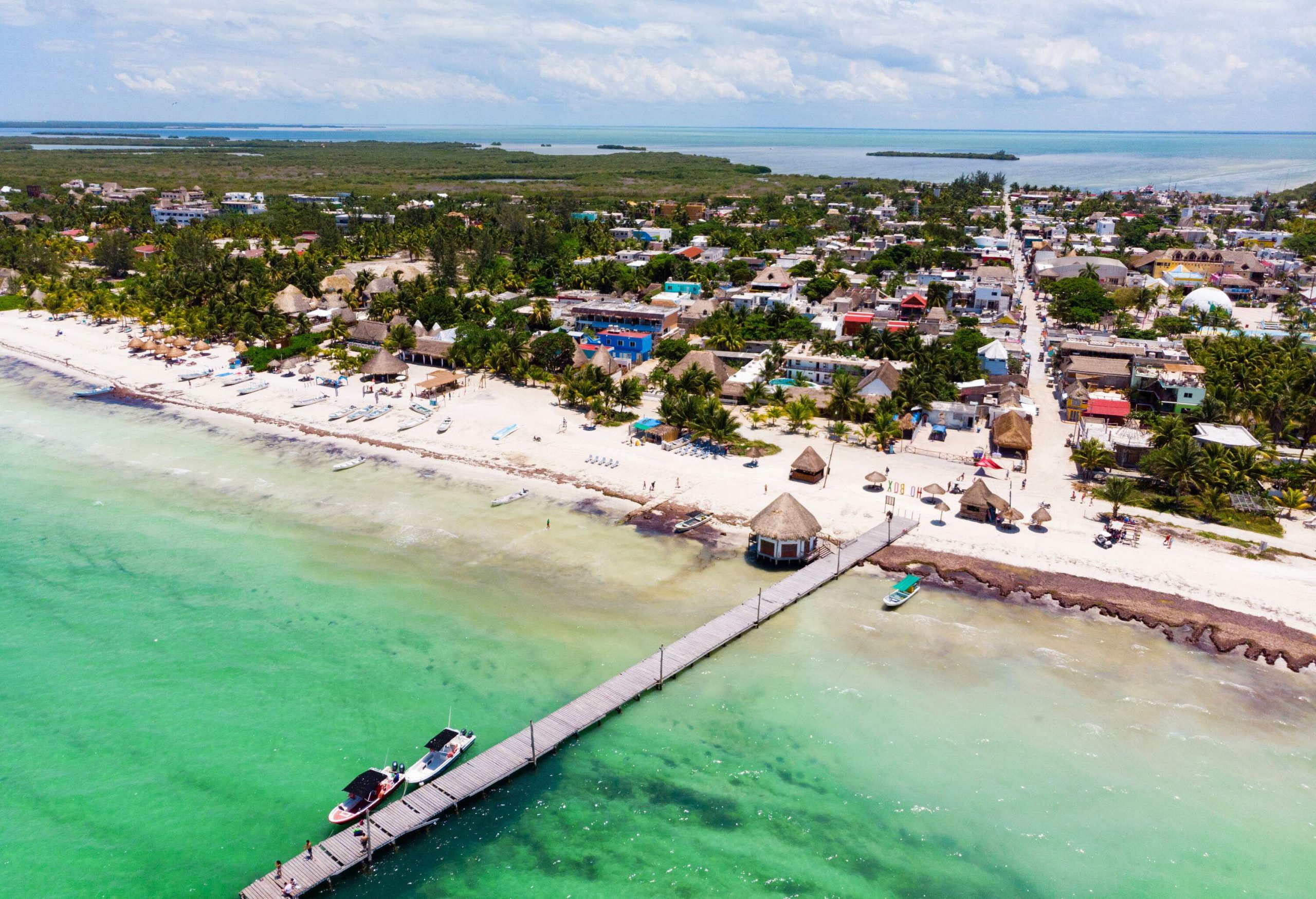 In a small seaside village, a long floating dock extends into the sea with two identical boats.