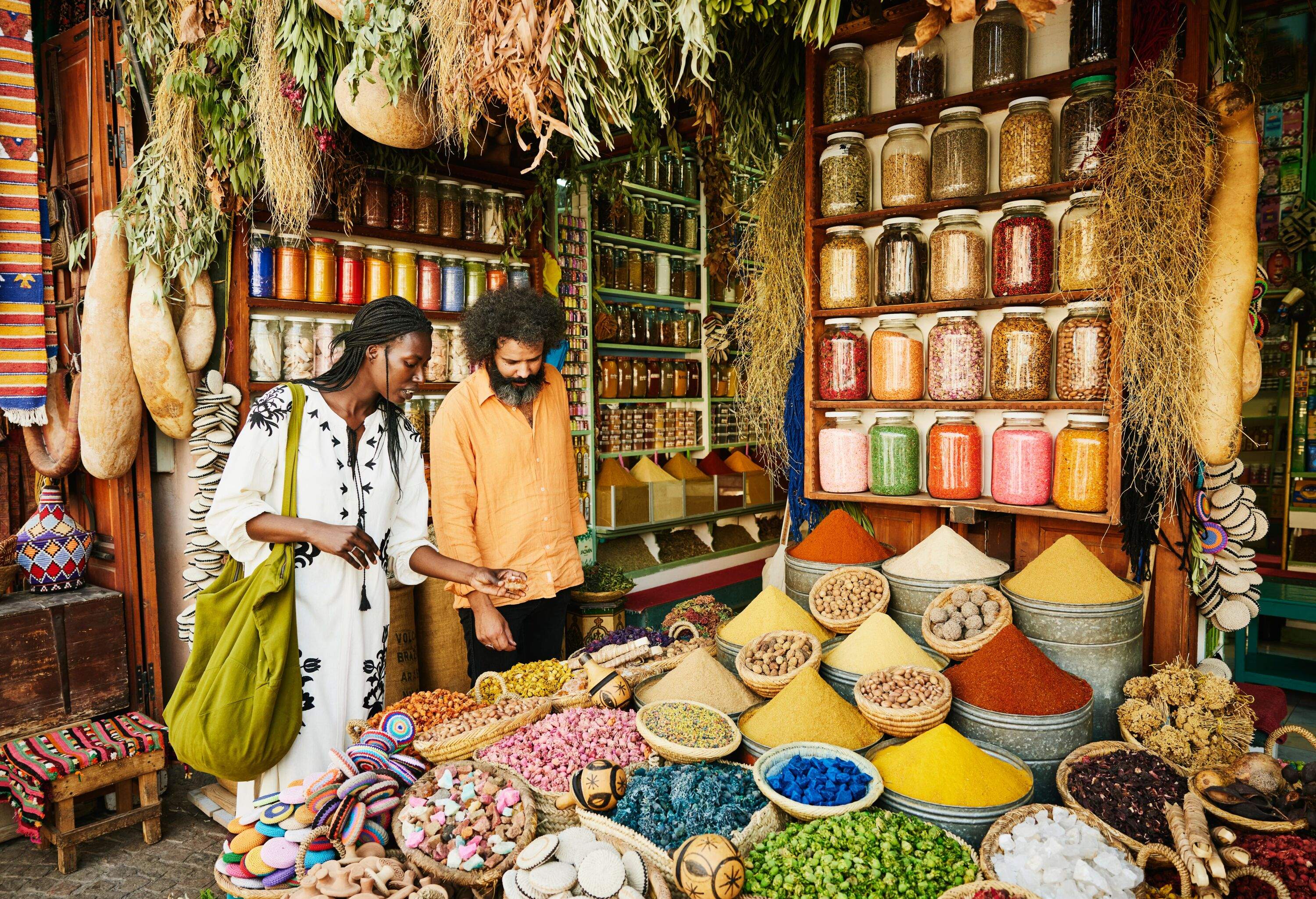 Wide shot of couple shopping in spice shop in the souks of Marrakech while on vacation