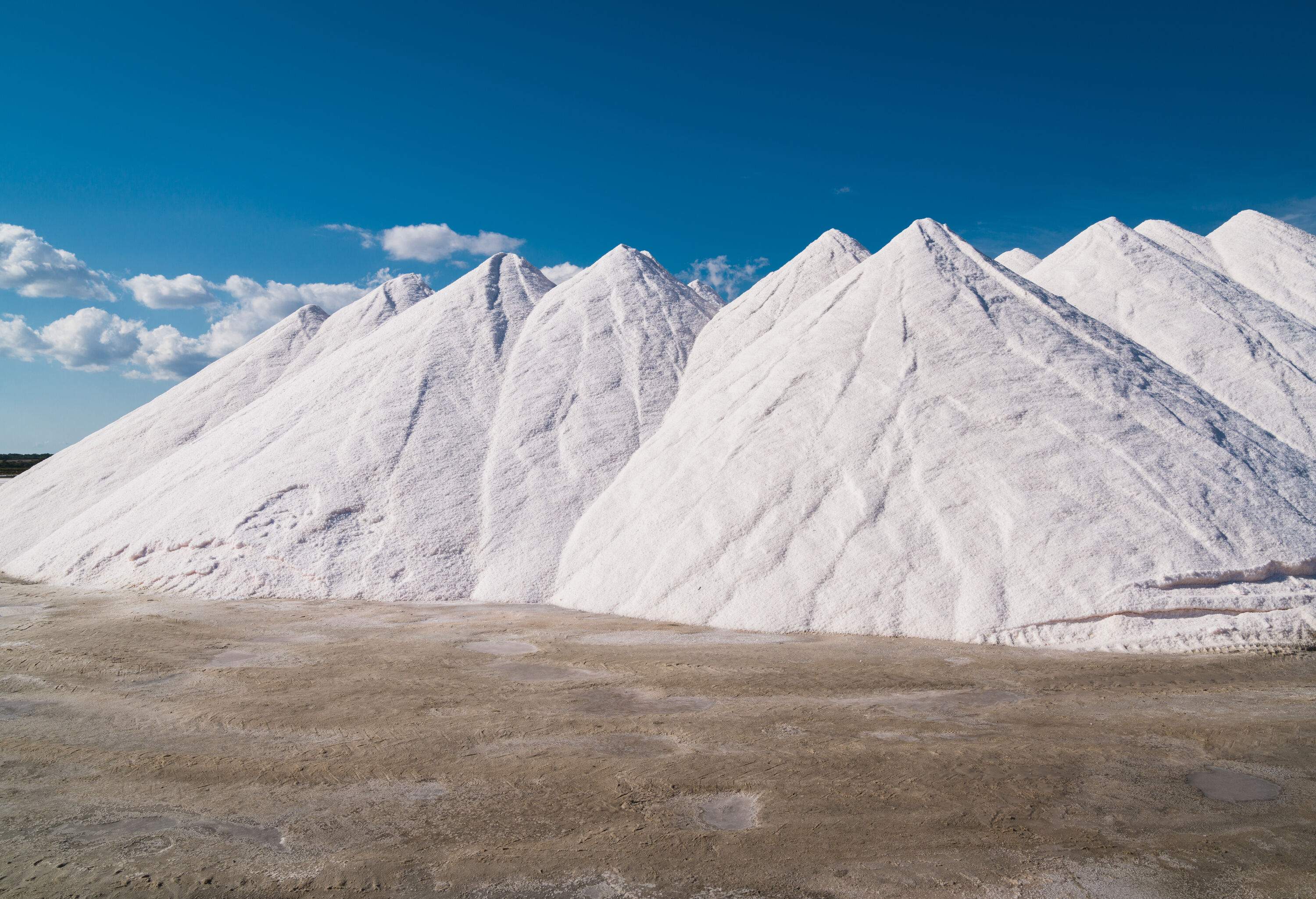 Sea salt is piled high under a sunny summer sky.